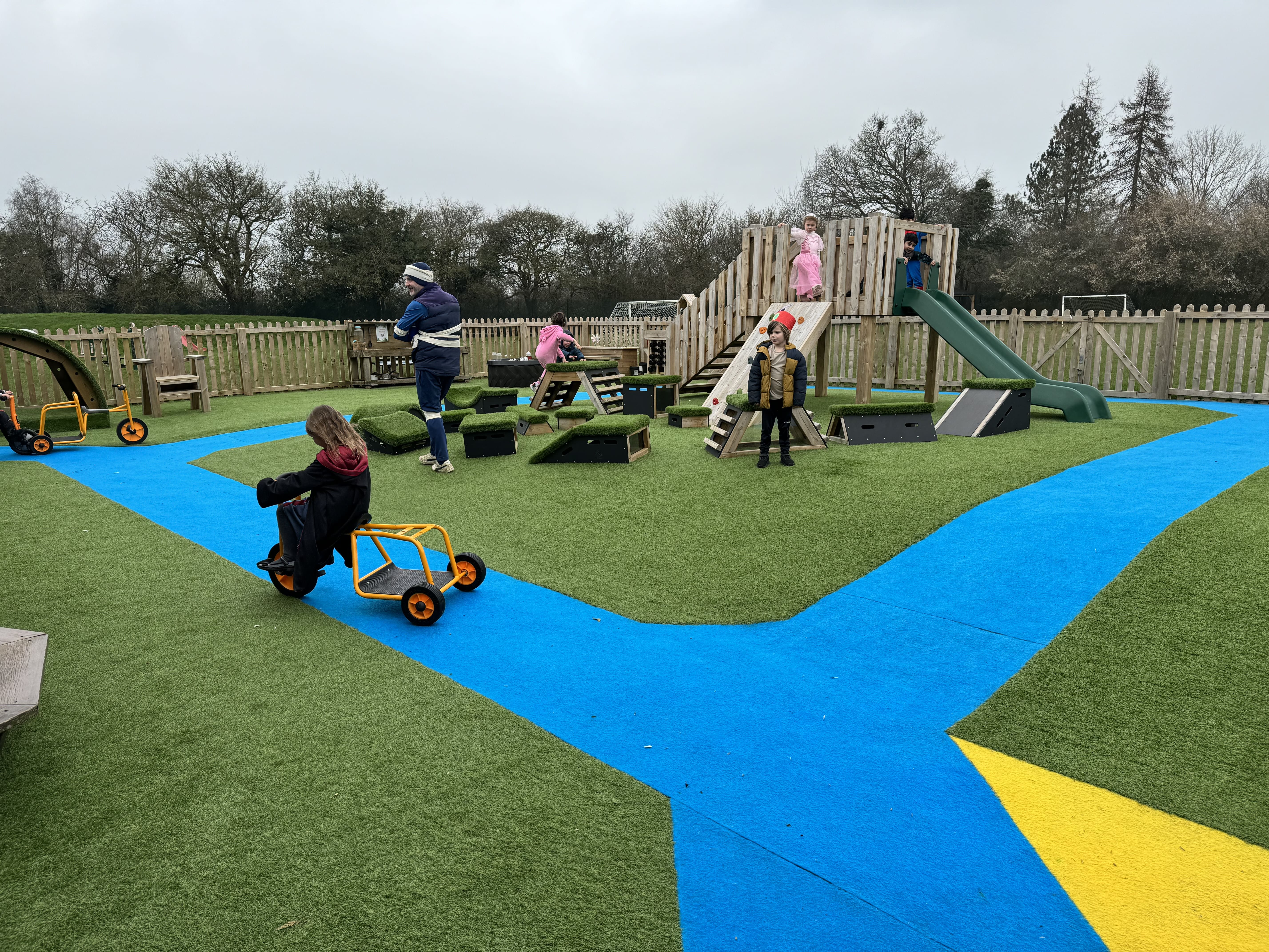 Children are playing on the artificial grass and are heading over to the modular Play Tower. Some children are already on the Play Tower and some other children are on the Get Set, Go! Blocks