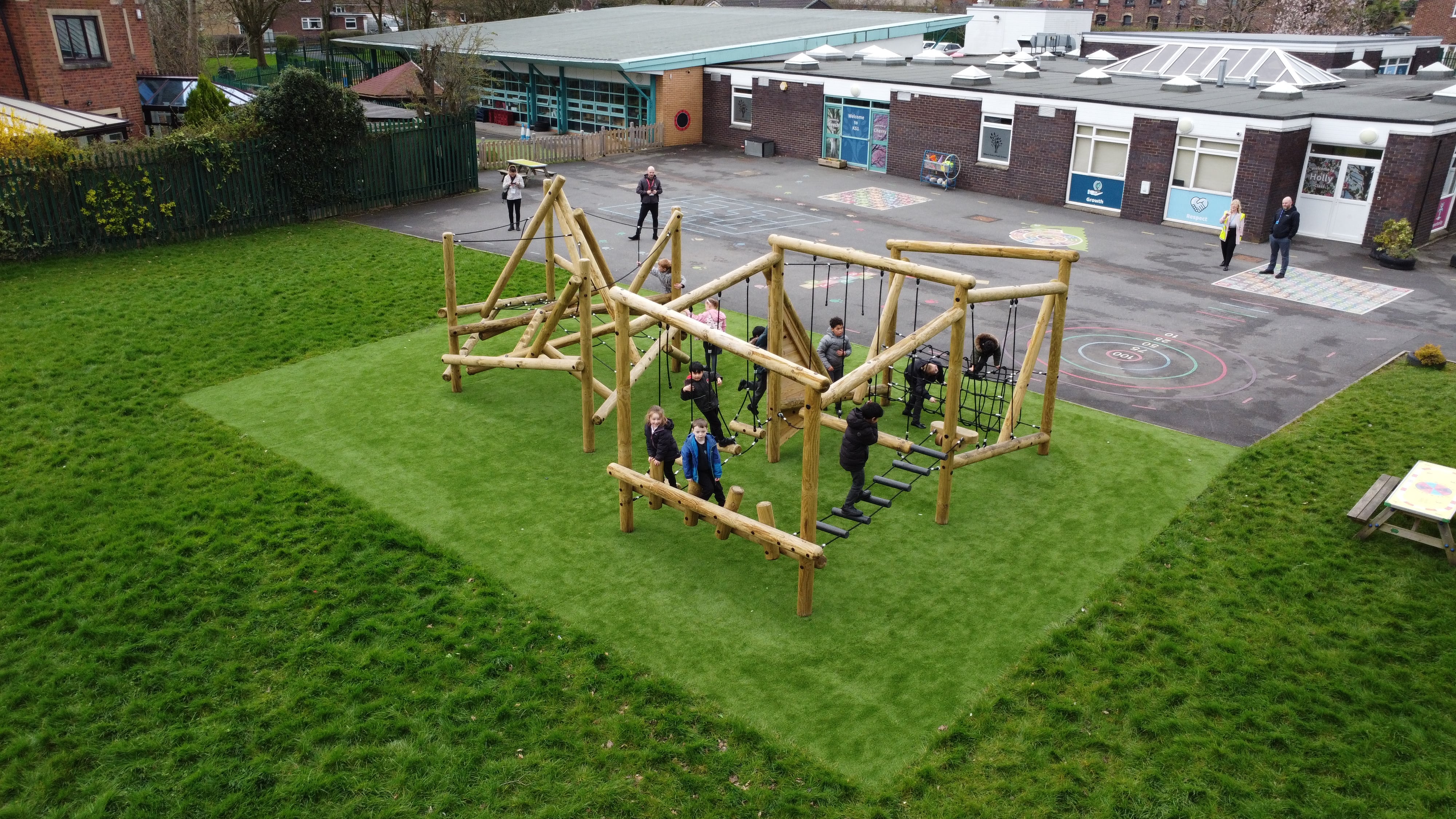 An image showing a huge climbing frame and a trim trail next to it. Both of these pieces of active play equipment have been installed on artificial grass turf.