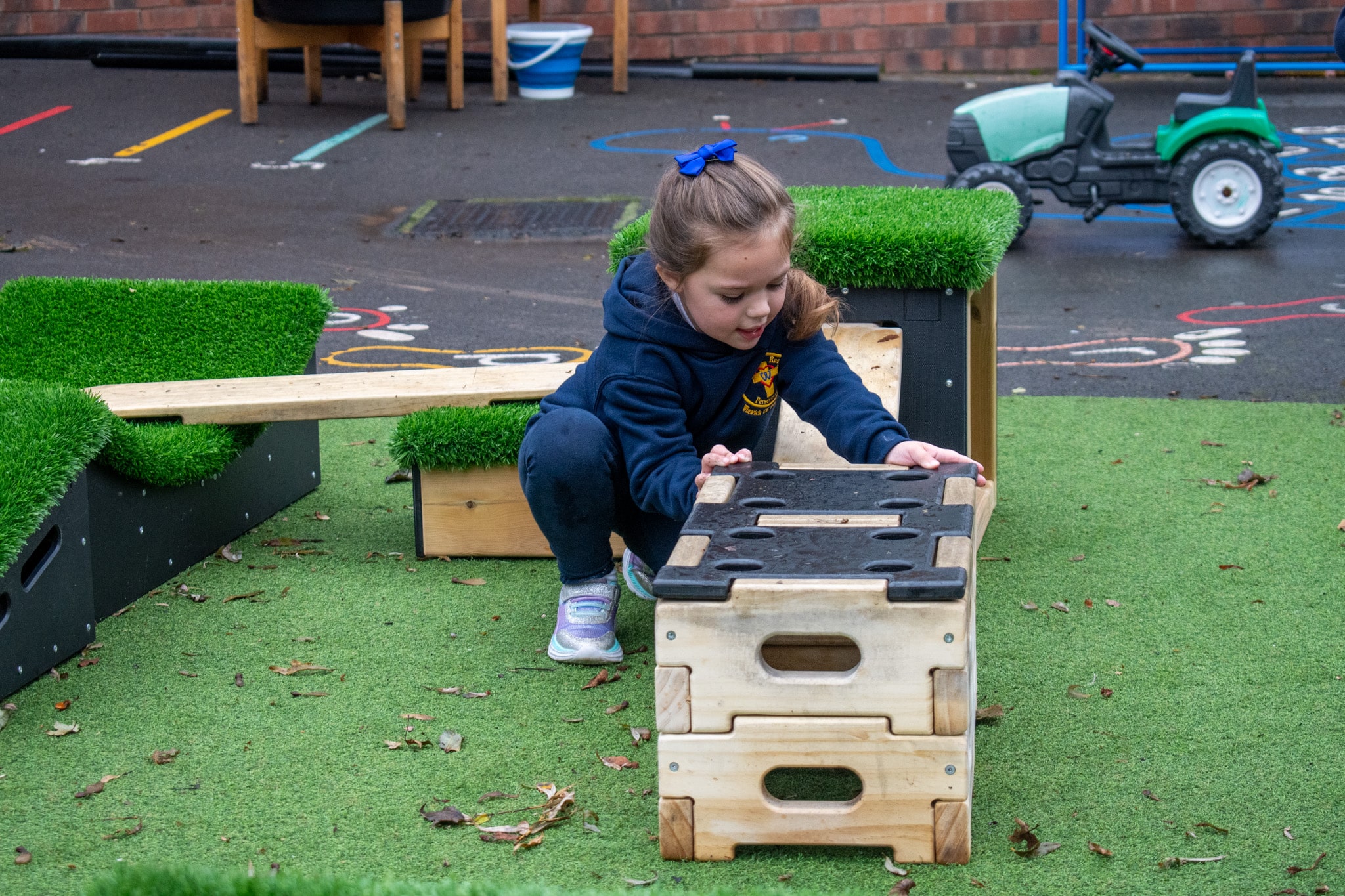 A little girl is attaching a Stokbord lid to the Play Builder blocks. Behind the girl, a variety of Get Set, Go! Blocks.