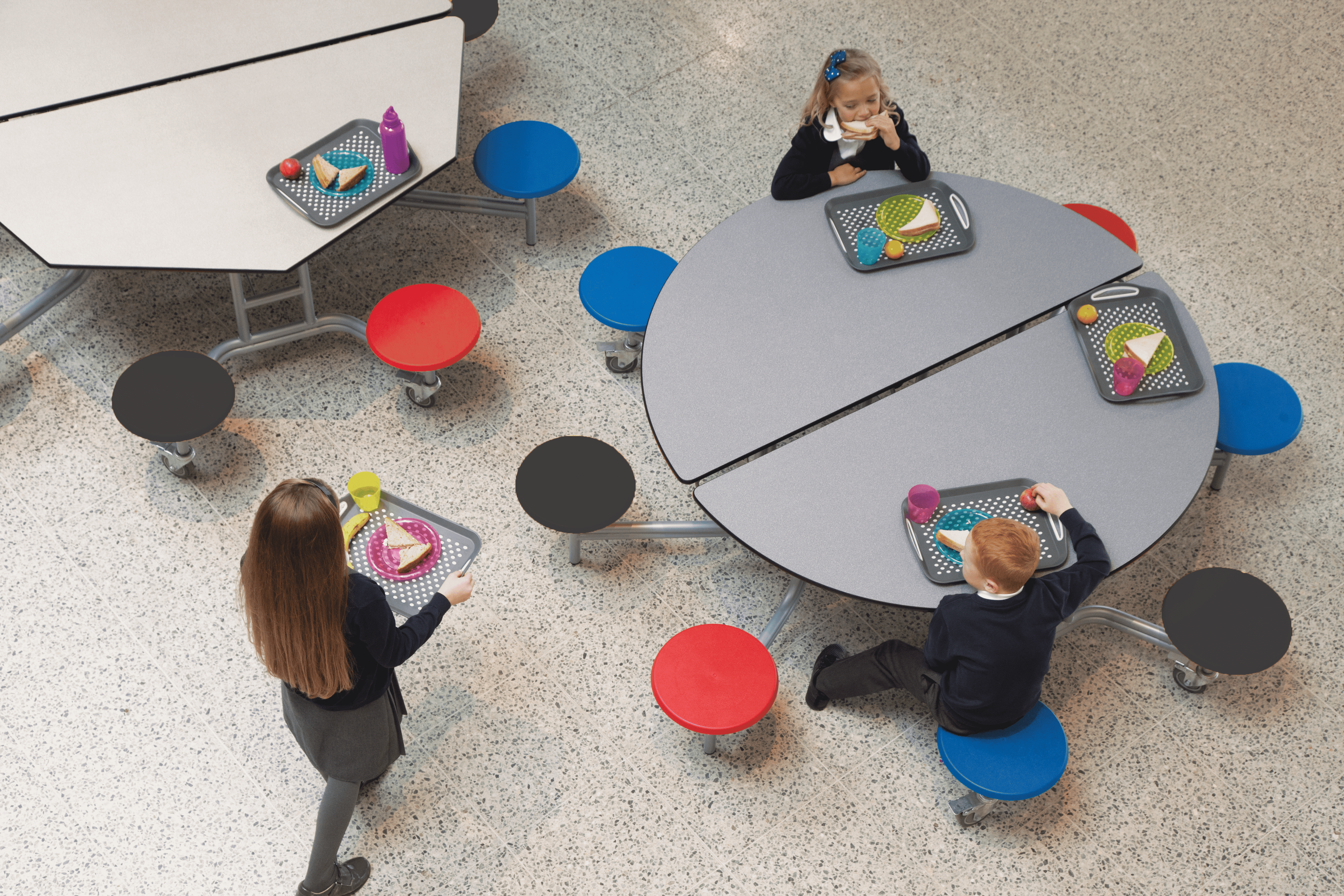 A group of children are sat at a 8 seater round school dining table.