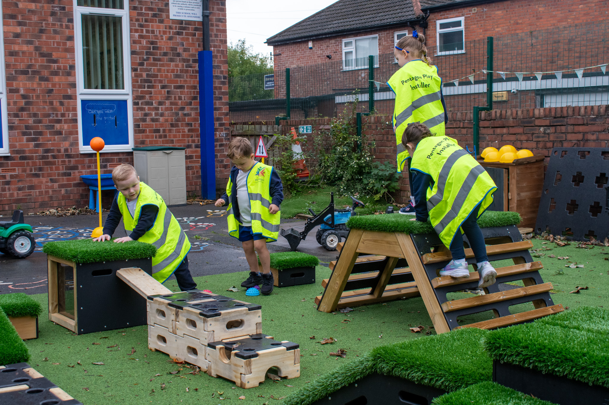 A group of 4 children are playing on the Sports Premium Discoverer package, which includes Get Set, Go! Blocks and Play Builder pieces. The children have set up the equipment on artificial grass.