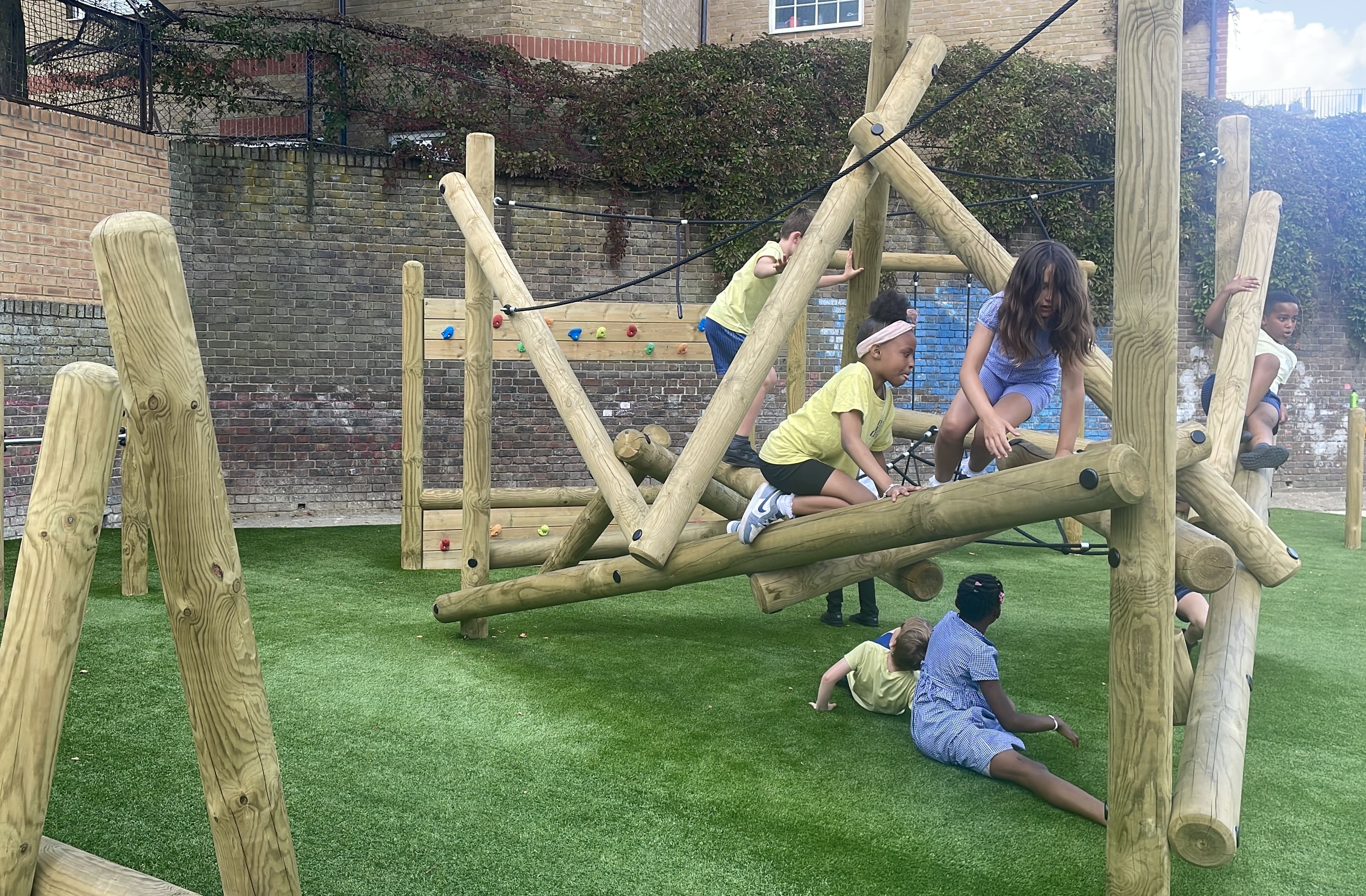 Children are playing on the Bowfell Climber. A couple of children are sat underneath the structure, whilst the majority of them are on top