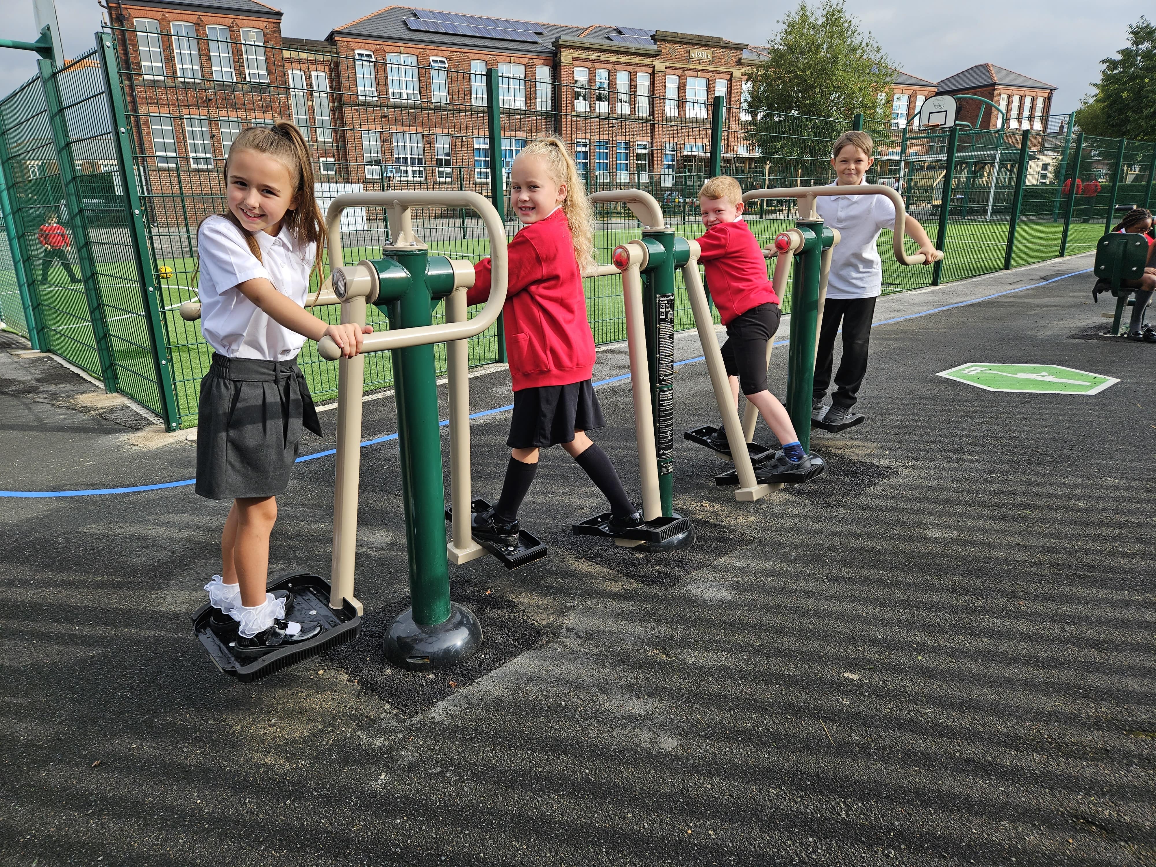 4 children are exercising on a double air walker and are looking at the camera and smiling.