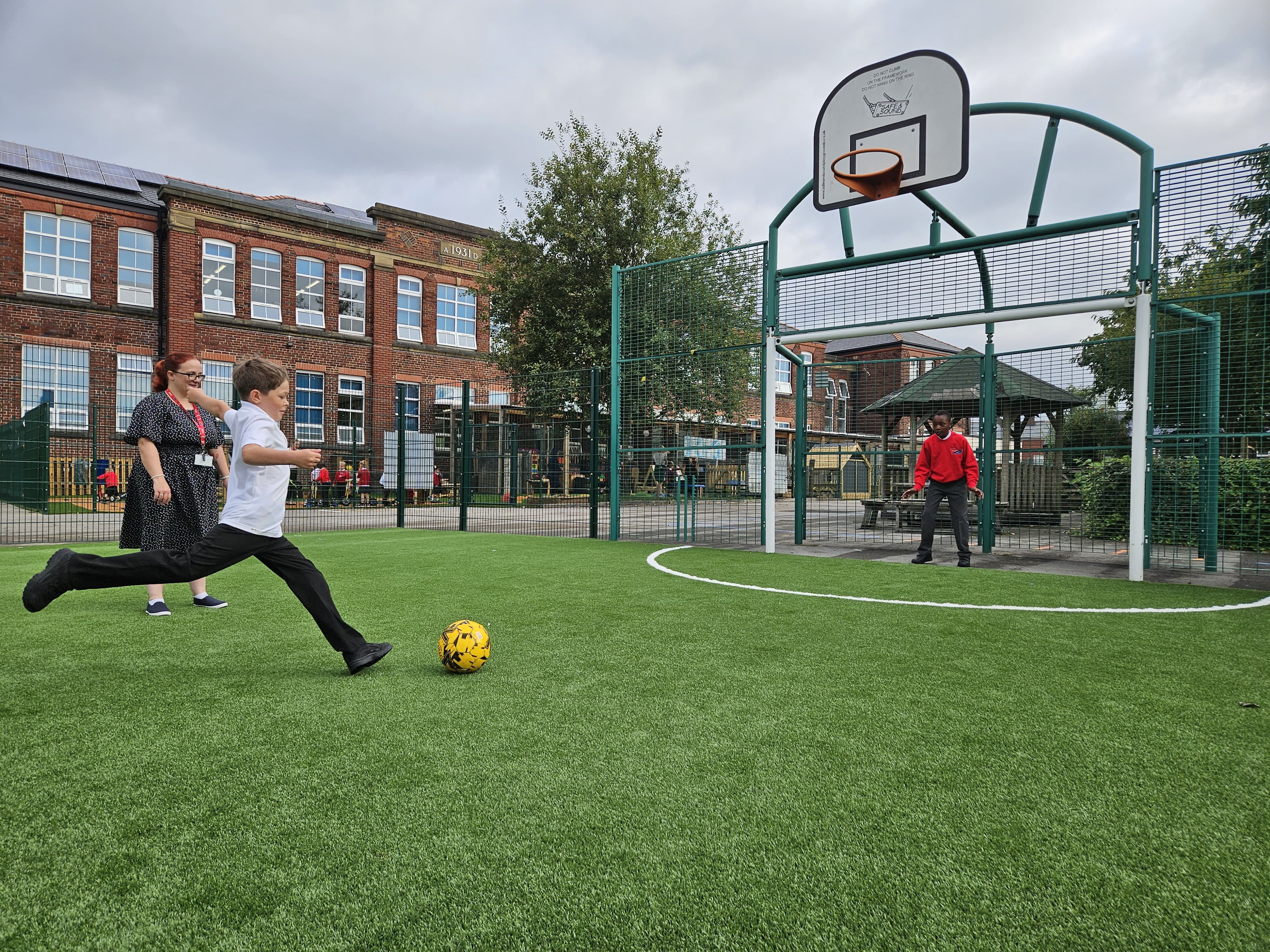 A boy is taking a penalty kick on a MUGA installed by Pentagon Play. Another child is stood in goal and is waiting for the shot.