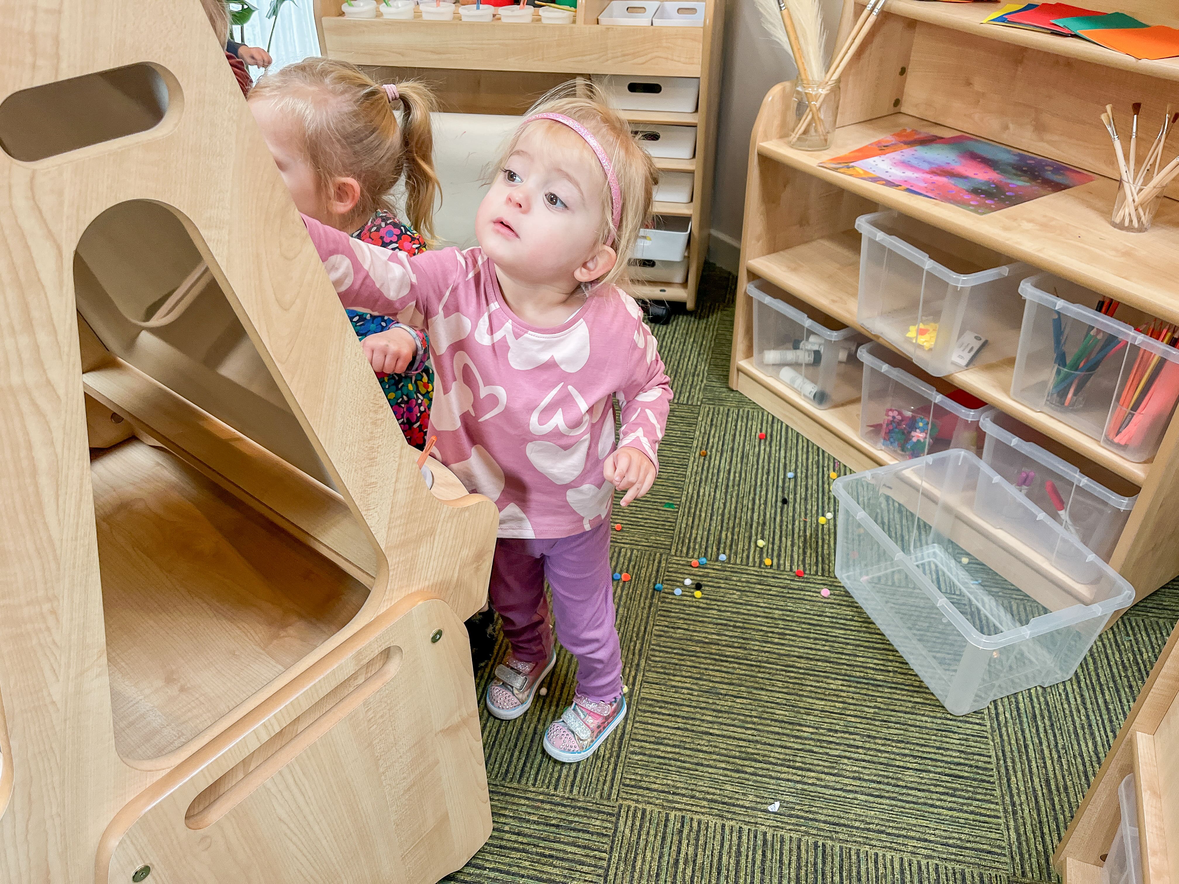 2 little girls are drawing on the Millhouse Art Easel and are fully emersed in their creative session. The Welsh Dresser and Continuous Provision Trolley can be seen in the background.