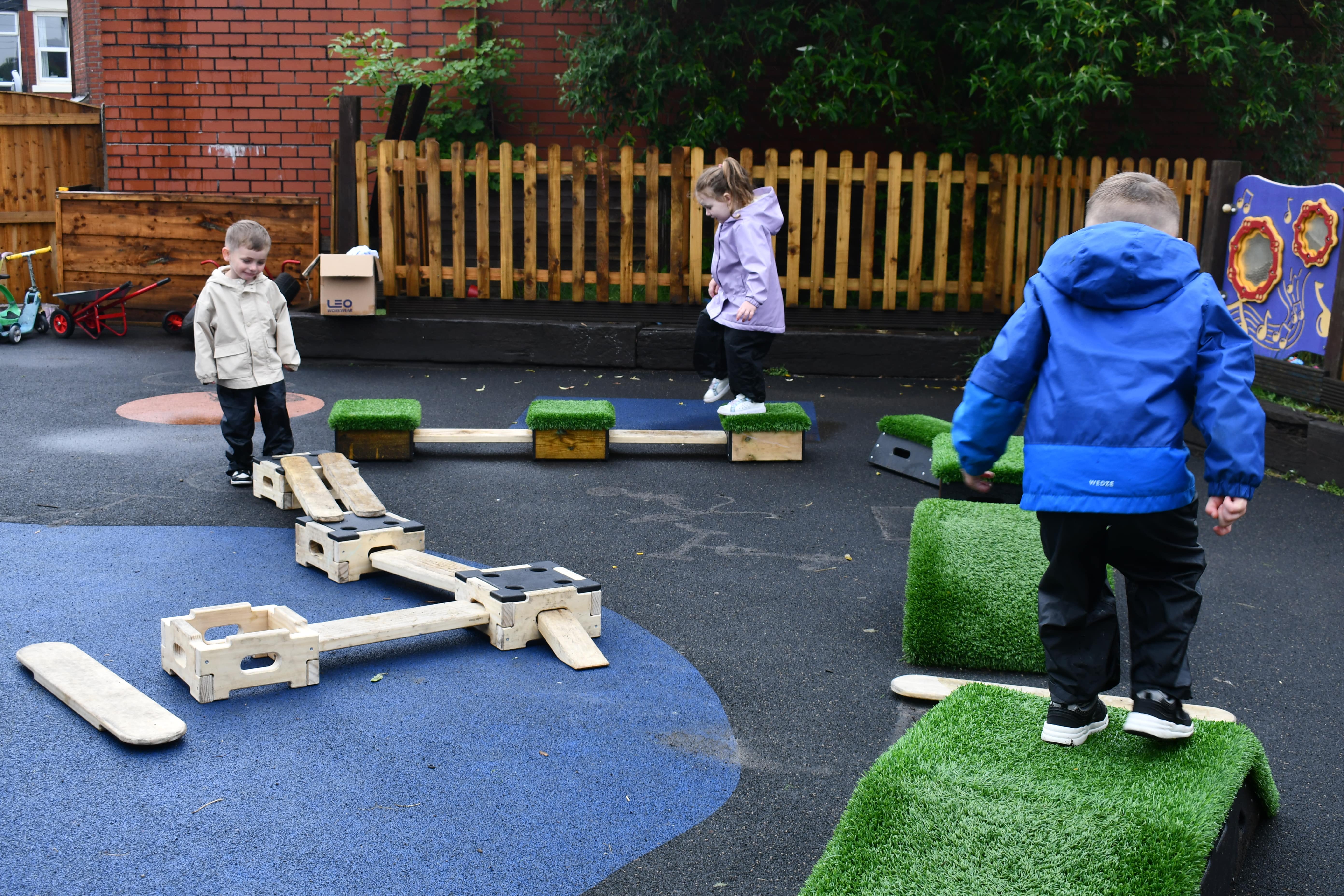 Three children are playing on the Sports Premium Adventurer Set, which has been placed on top of wetpour