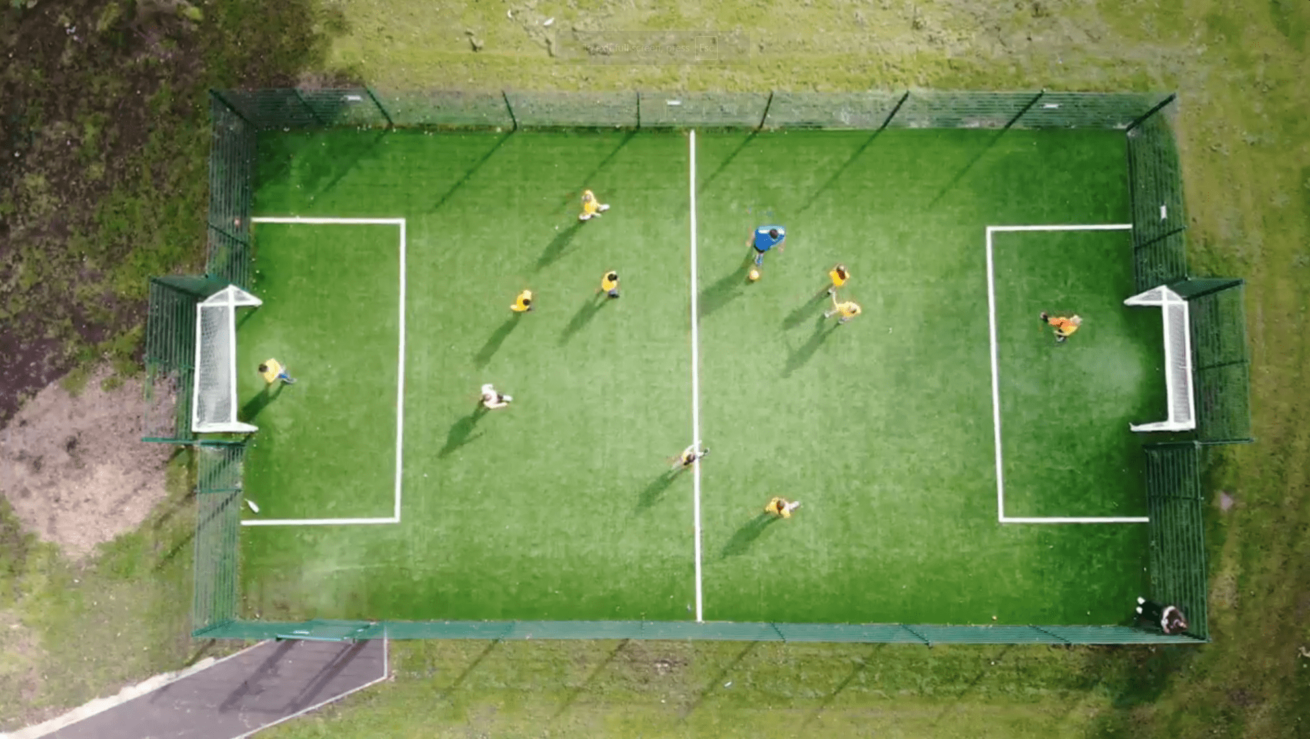 A birdseye view showcasing the MUGA that has been installed by Pentagon Play. A group of children and a teacher can be seen on the football pitch.