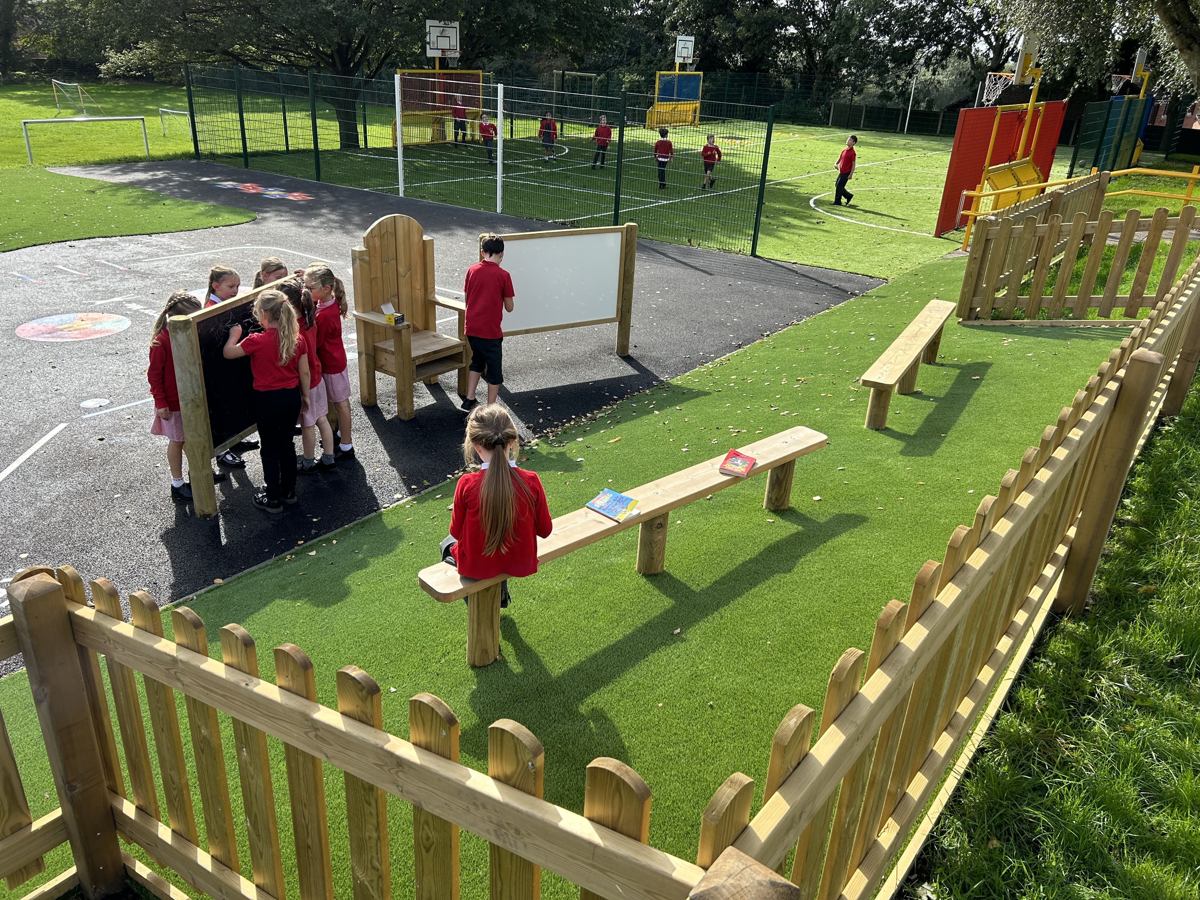 Children are gathering around a chalkboard on posts as they draw different shapes and words.