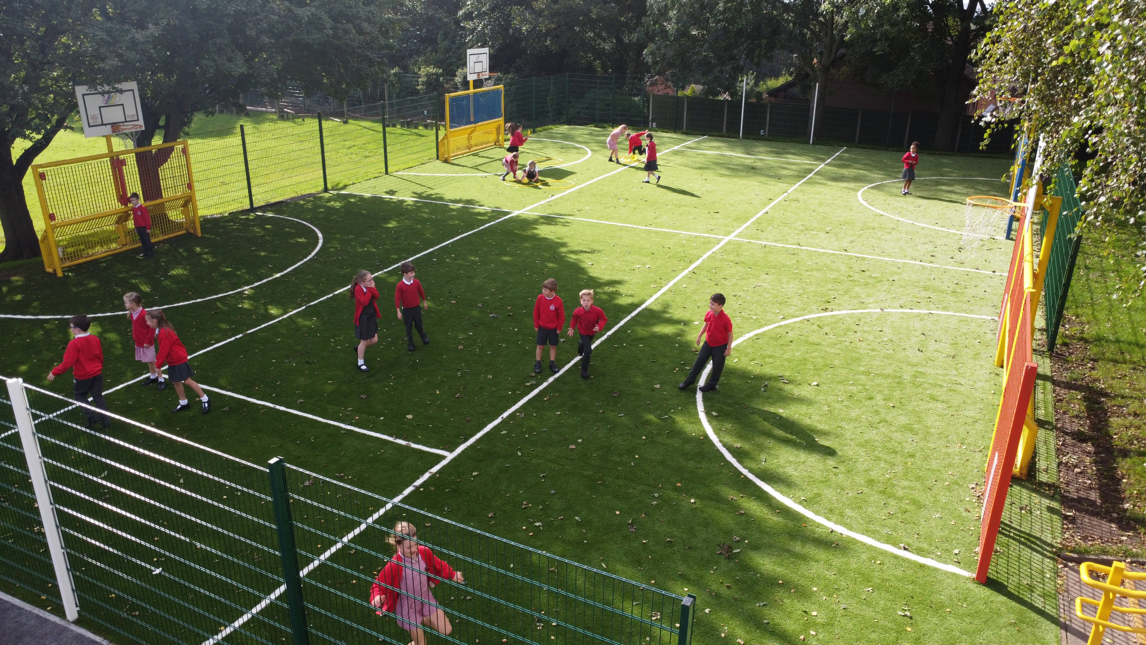 A group of children are playing a game of football on a Playturf artificial grass MUGA pitch.