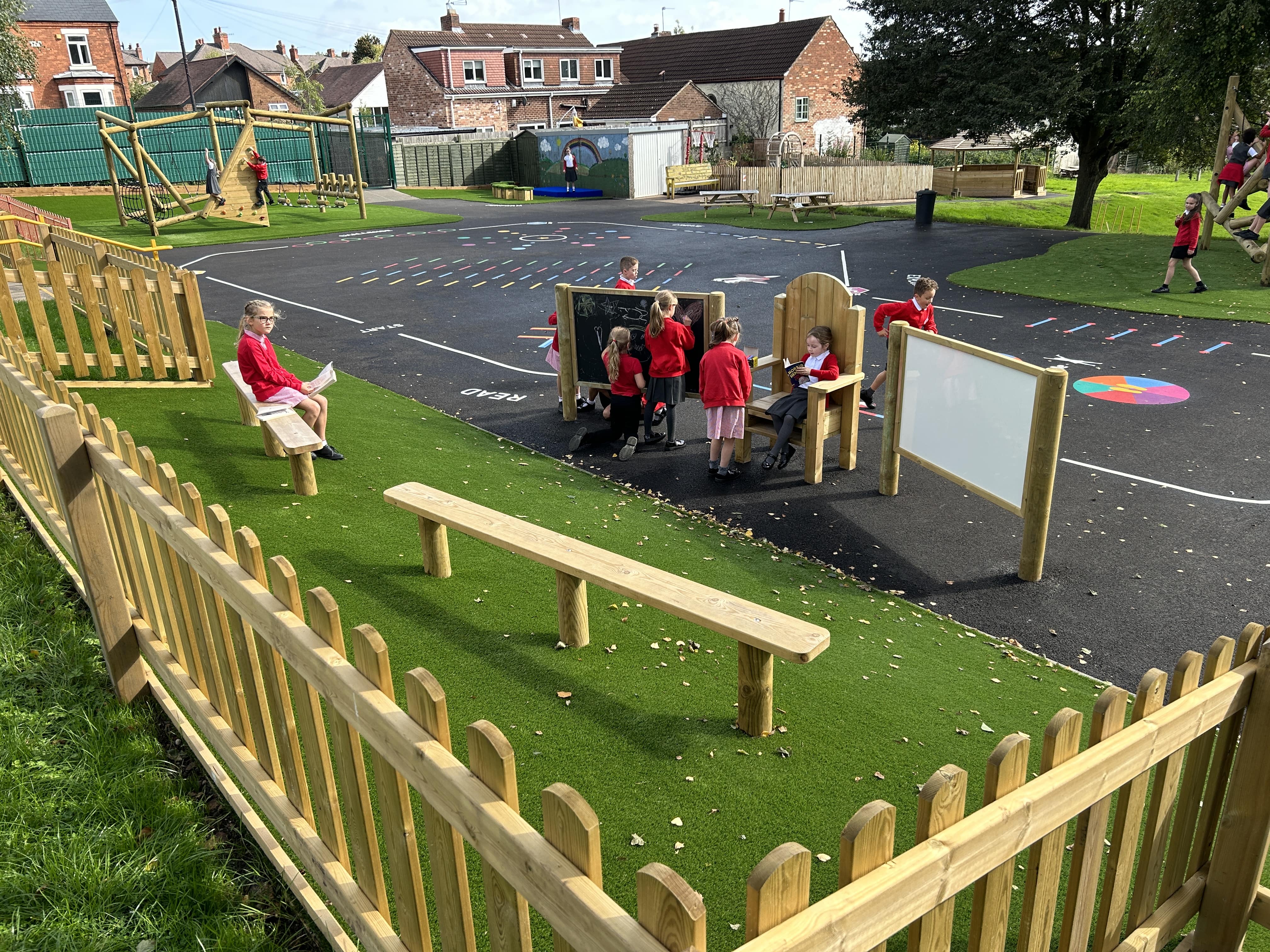 A group of children are sat in a communication zone with a variety of play equipment.