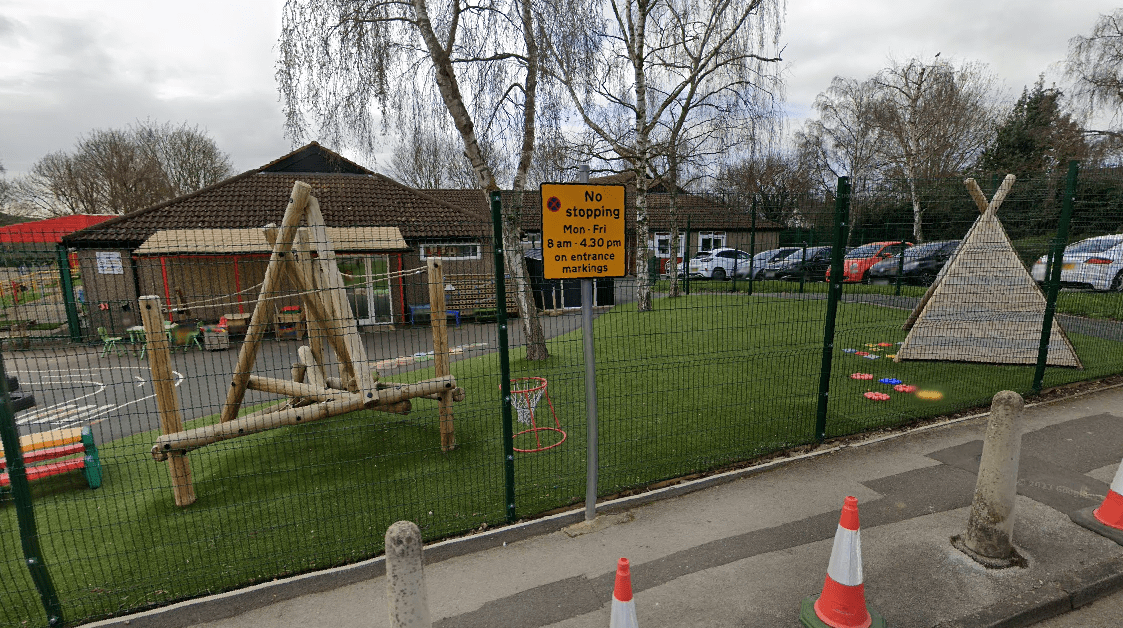 The building of a primary school with a early years playground shown with a climbing frame and Wigwam present.