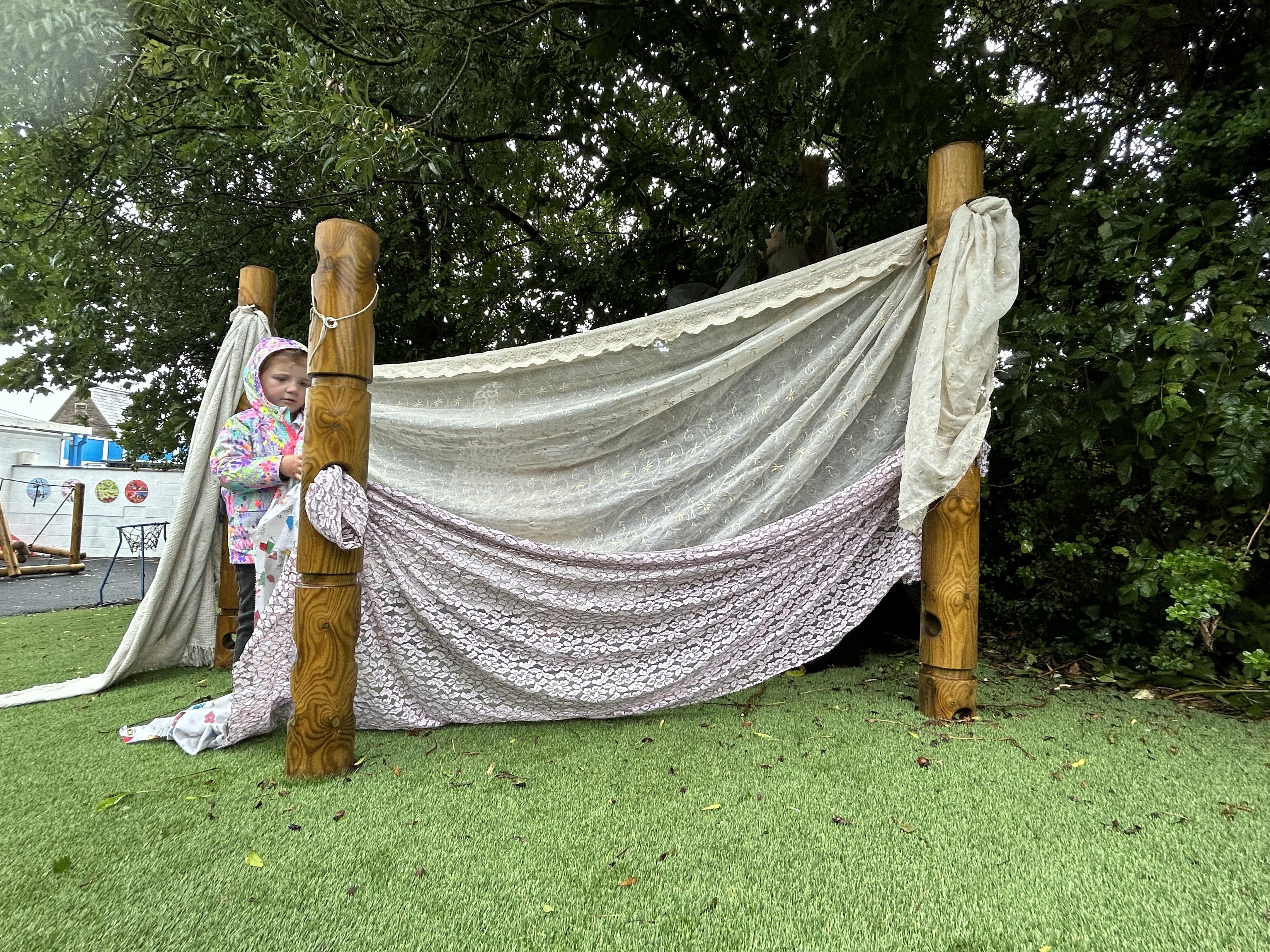 A little child is building a den using the Den Posts built and installed by Pentagon Play.