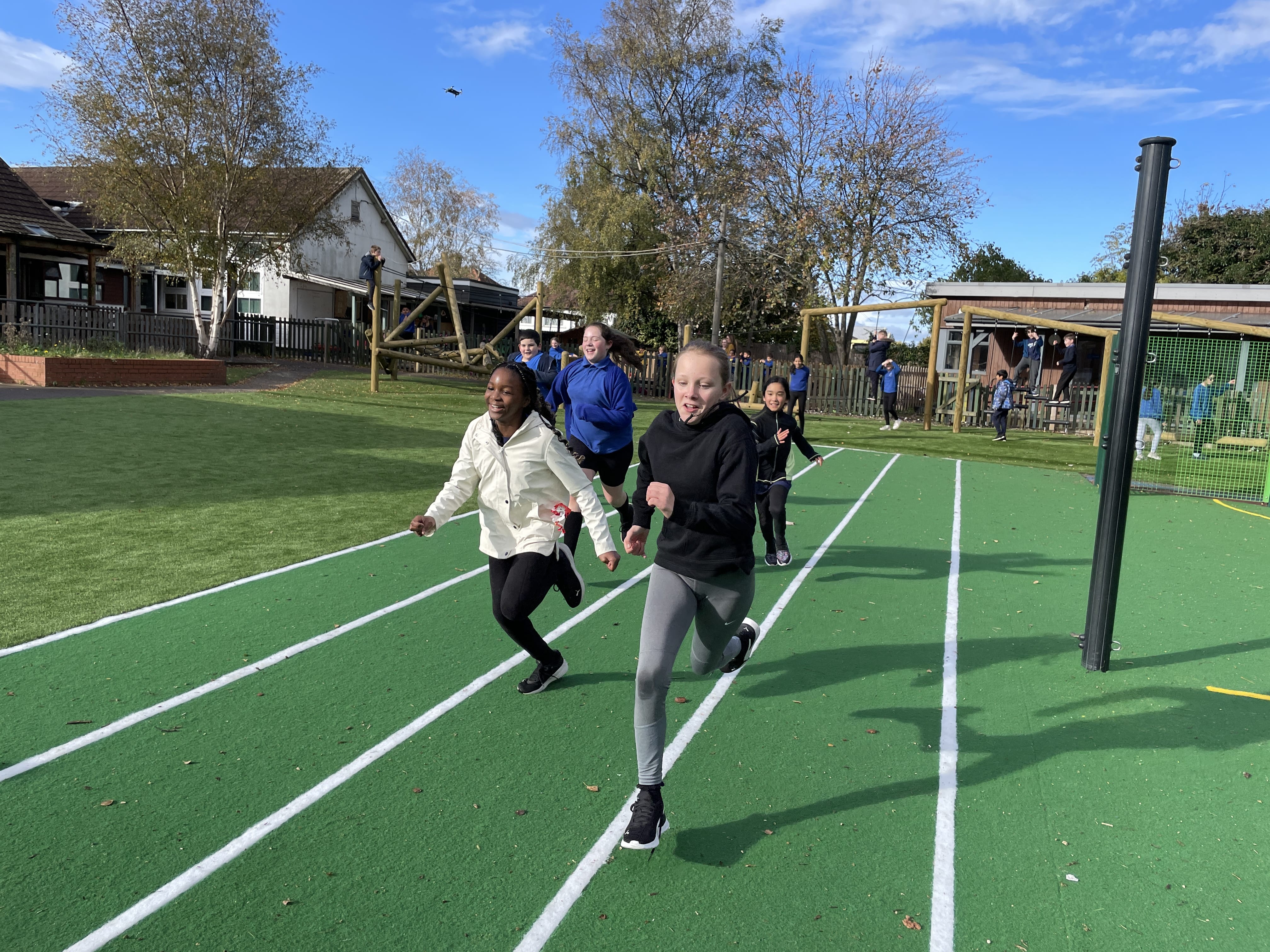 A group of children are having a race on the race track and are sprinting towards the camera.