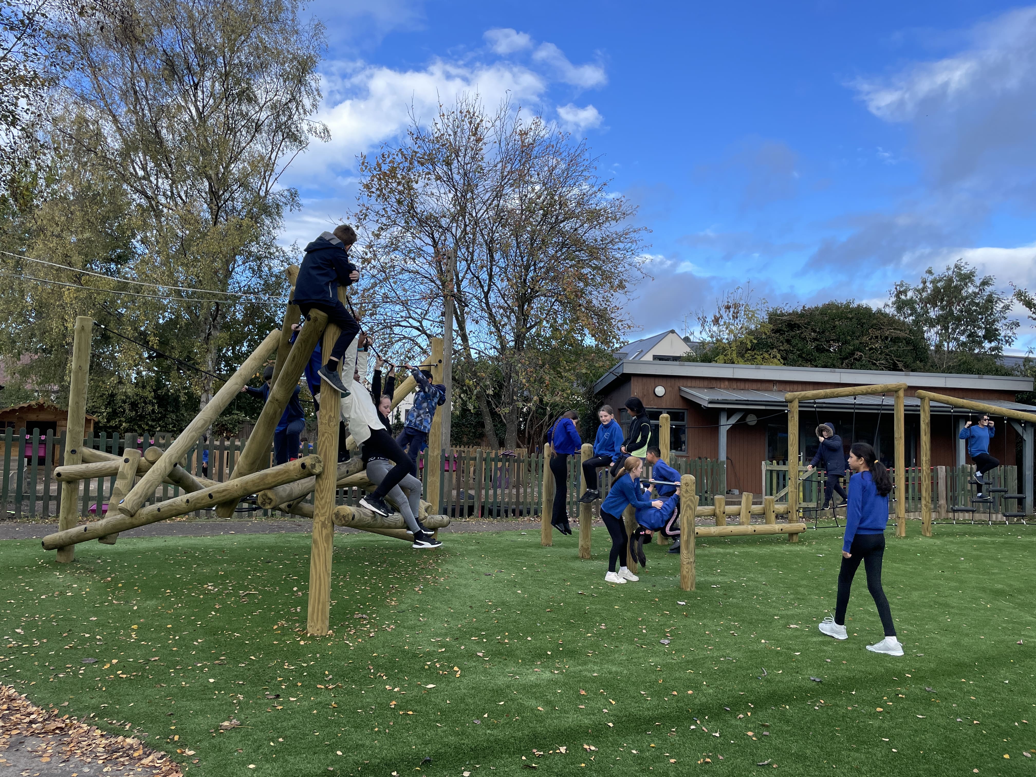 A group of children are playing on the climbing frame, with the other group of children are starting to conquer the trim trail. 