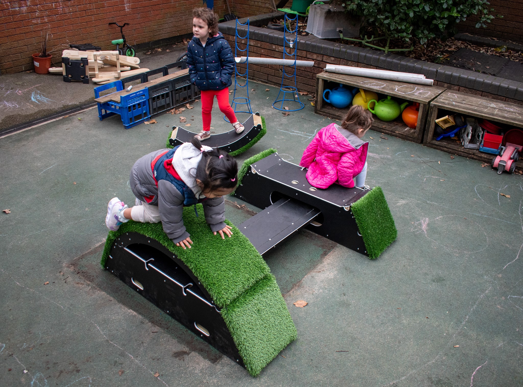 A group of children are playing on the Rockies and are using different parts of it for play.