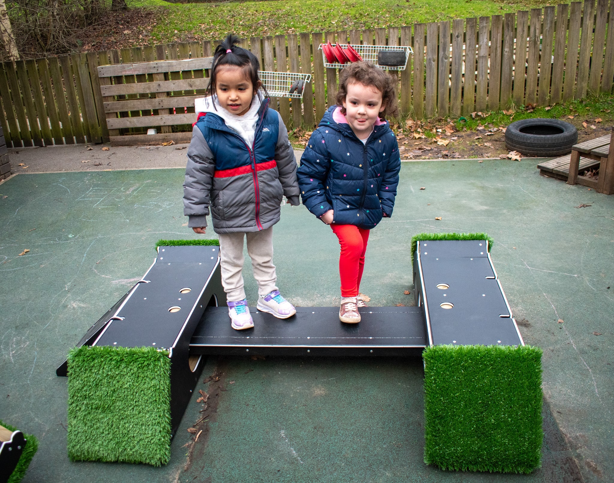 Two nursery children are stood on a new piece of freestanding play equipment called "The Rockies".