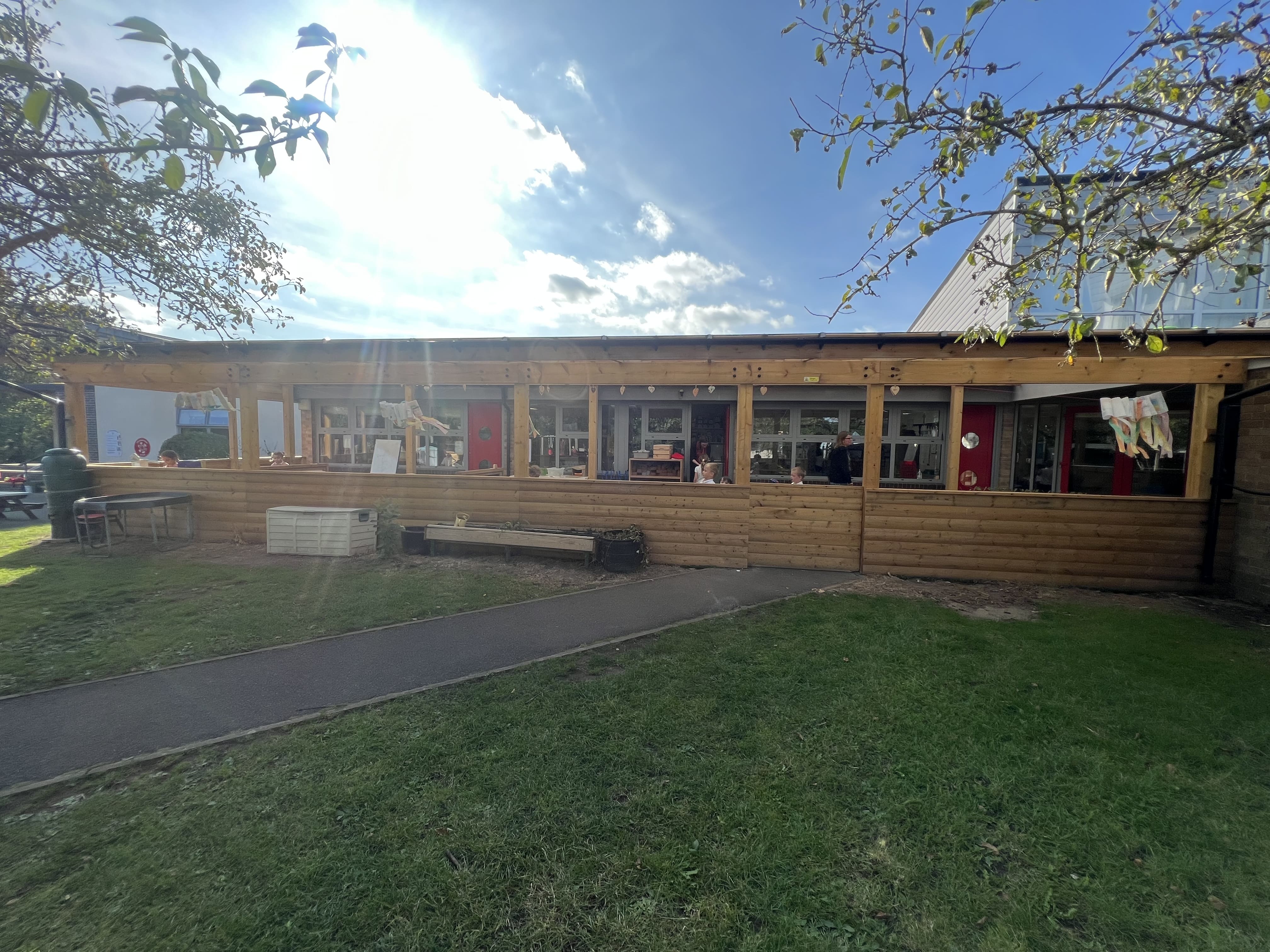 An outdoor canopy that has been attached to the side of a school to create an outdoor classroom.