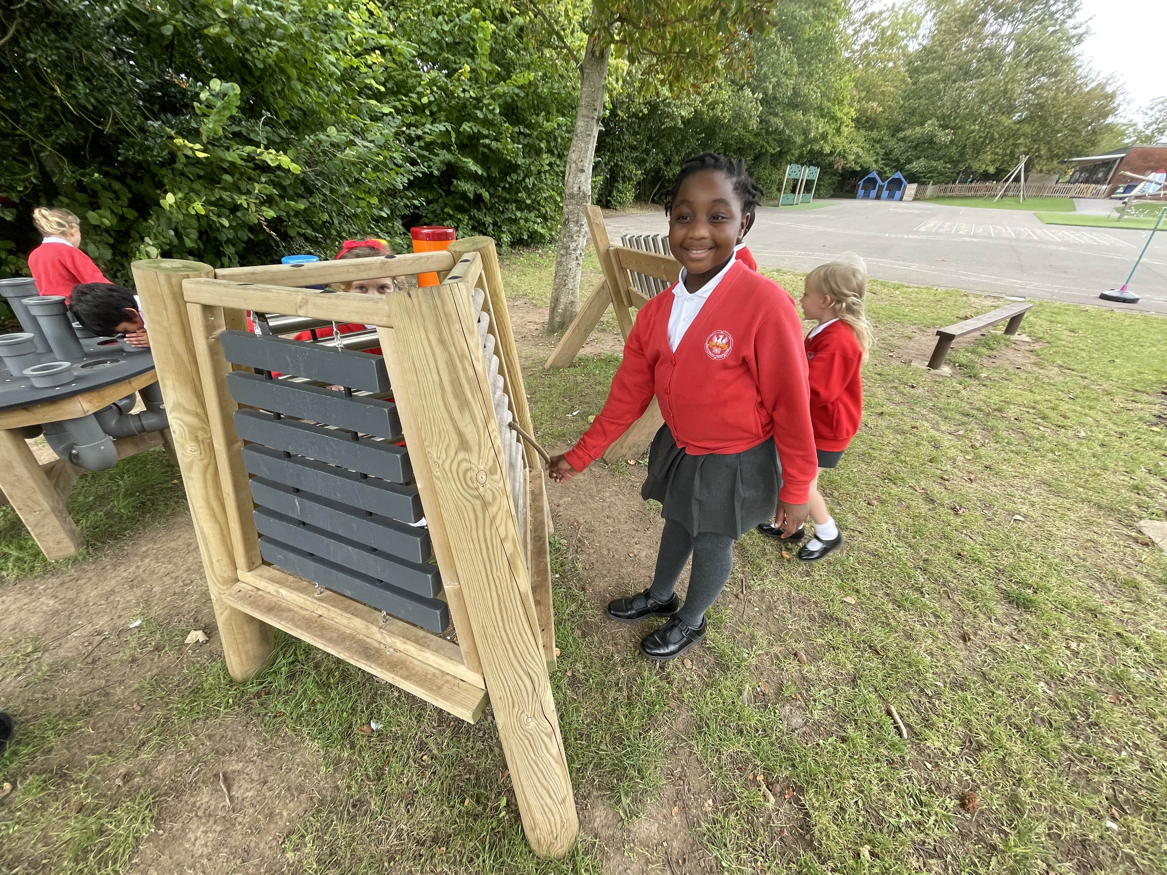 A child is playing an outdoor musical instrument and looks happy.