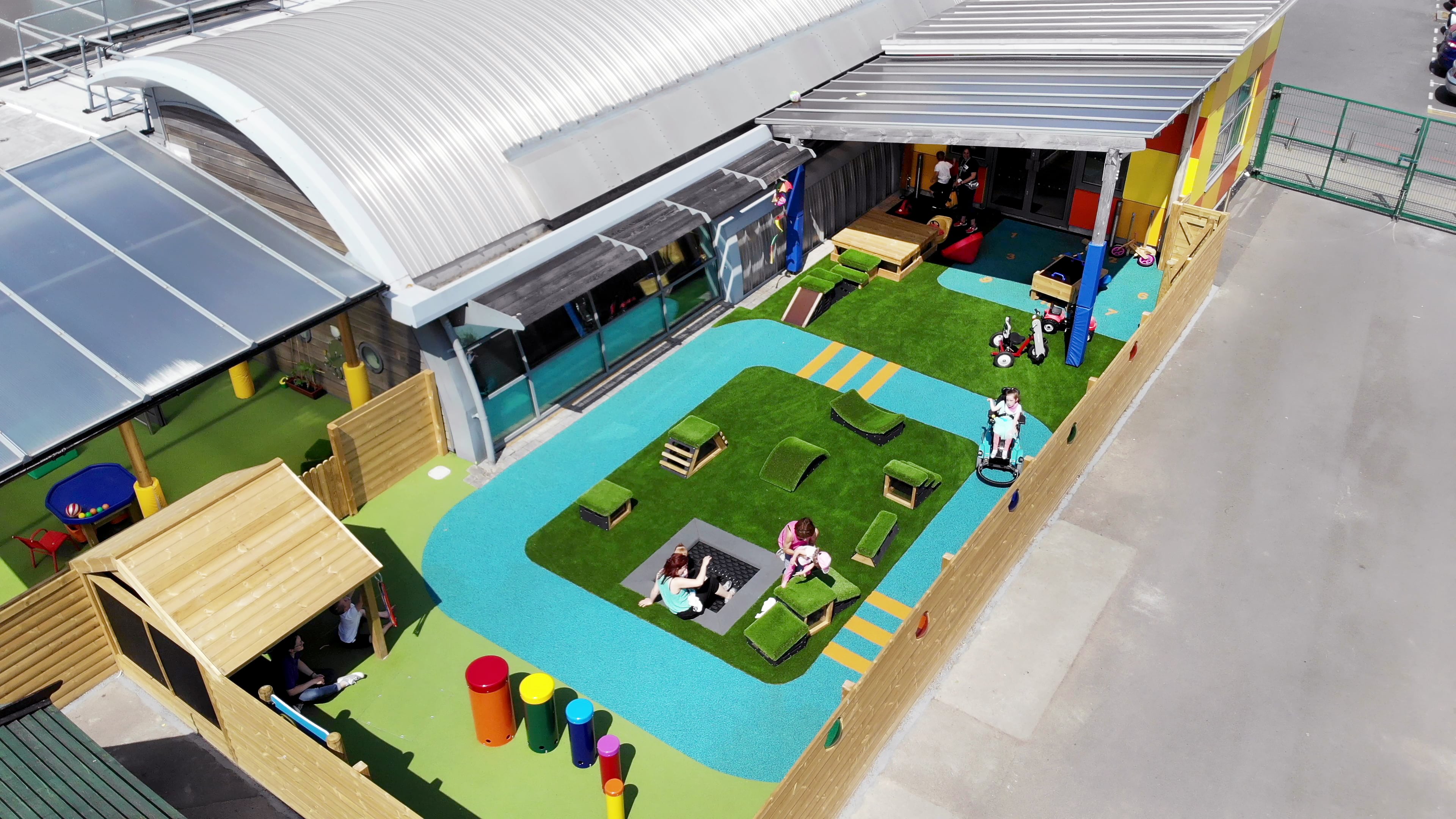 A playground for a SEN school, showcasing a variety of play equipment that is perfect for SEN children. Artificial grass and wetpour surfacing can be seen.