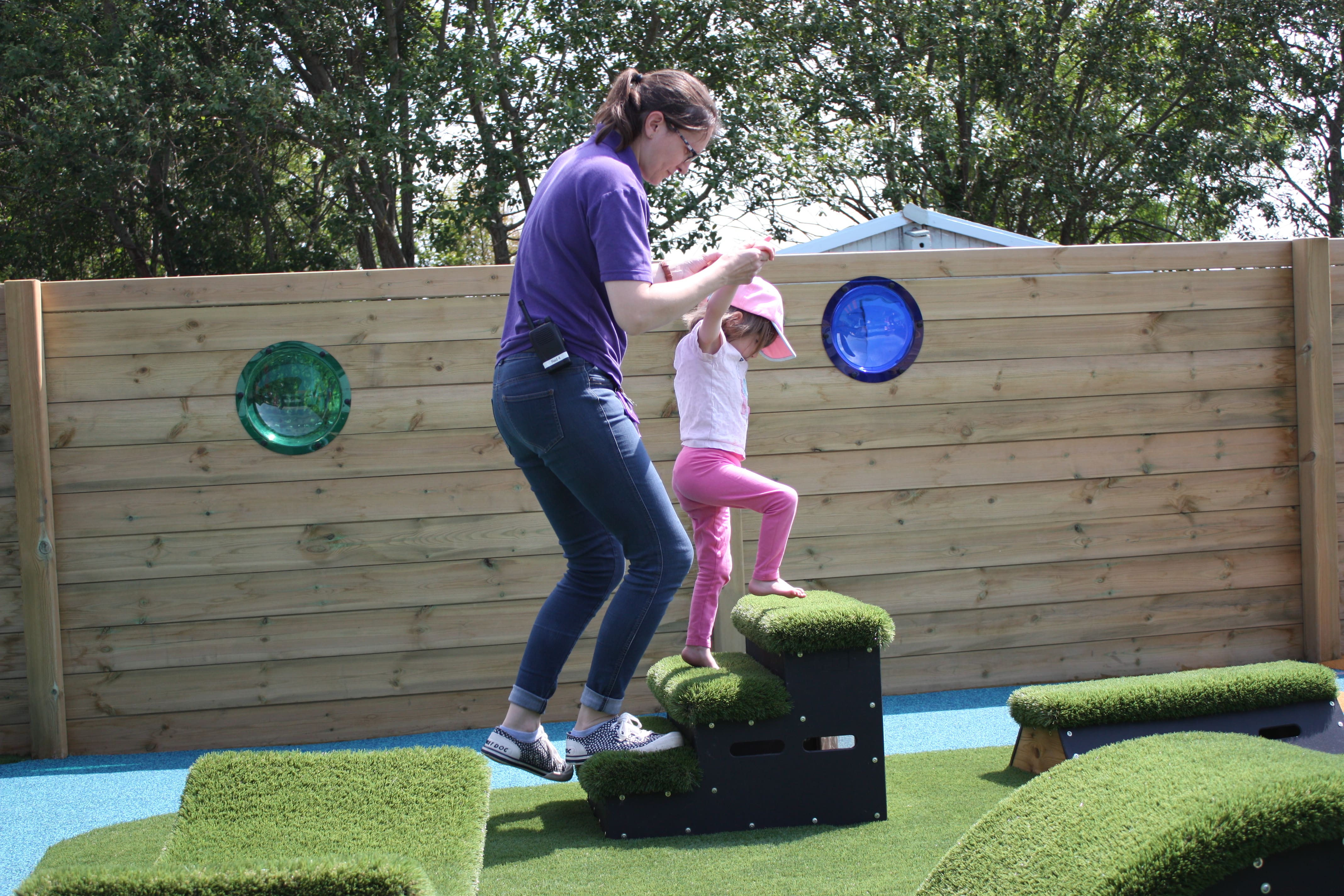 An EYFS SEN girl is being supported by a teacher to complete an obstacle course made from Get Set, Go! Blocks.