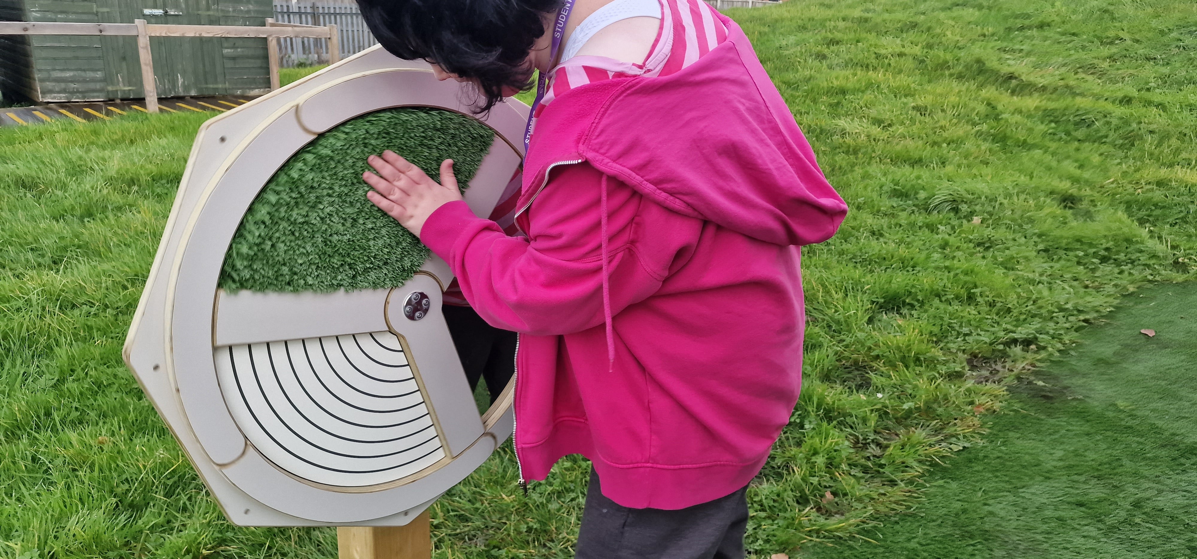 A SEN girl is rubbing her hand across the Sensory Spinner and is currently feeling the sense of artificial grass.