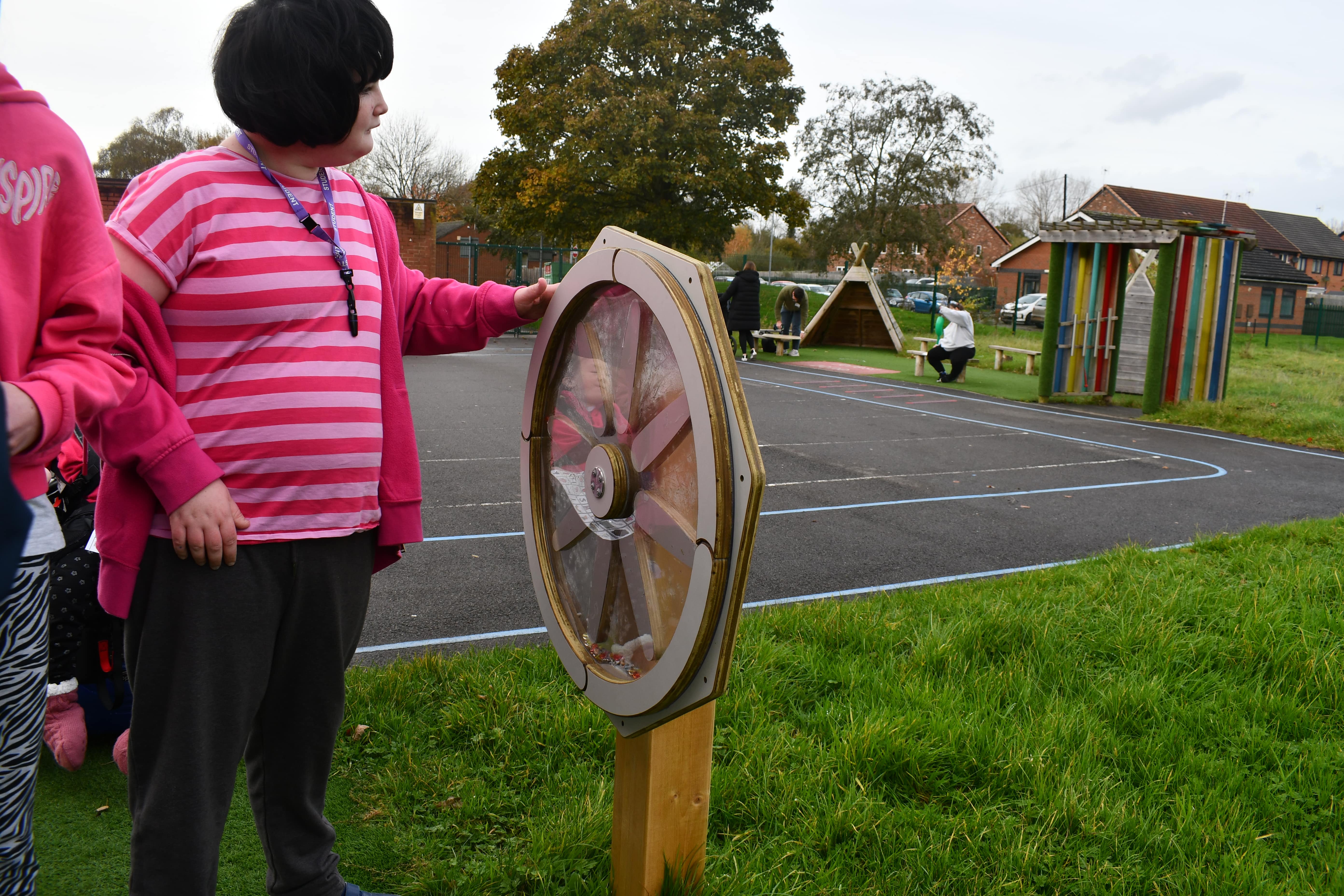 A young SEN girl is playing with a Sensory Spinner and looks interested by the play equipment.