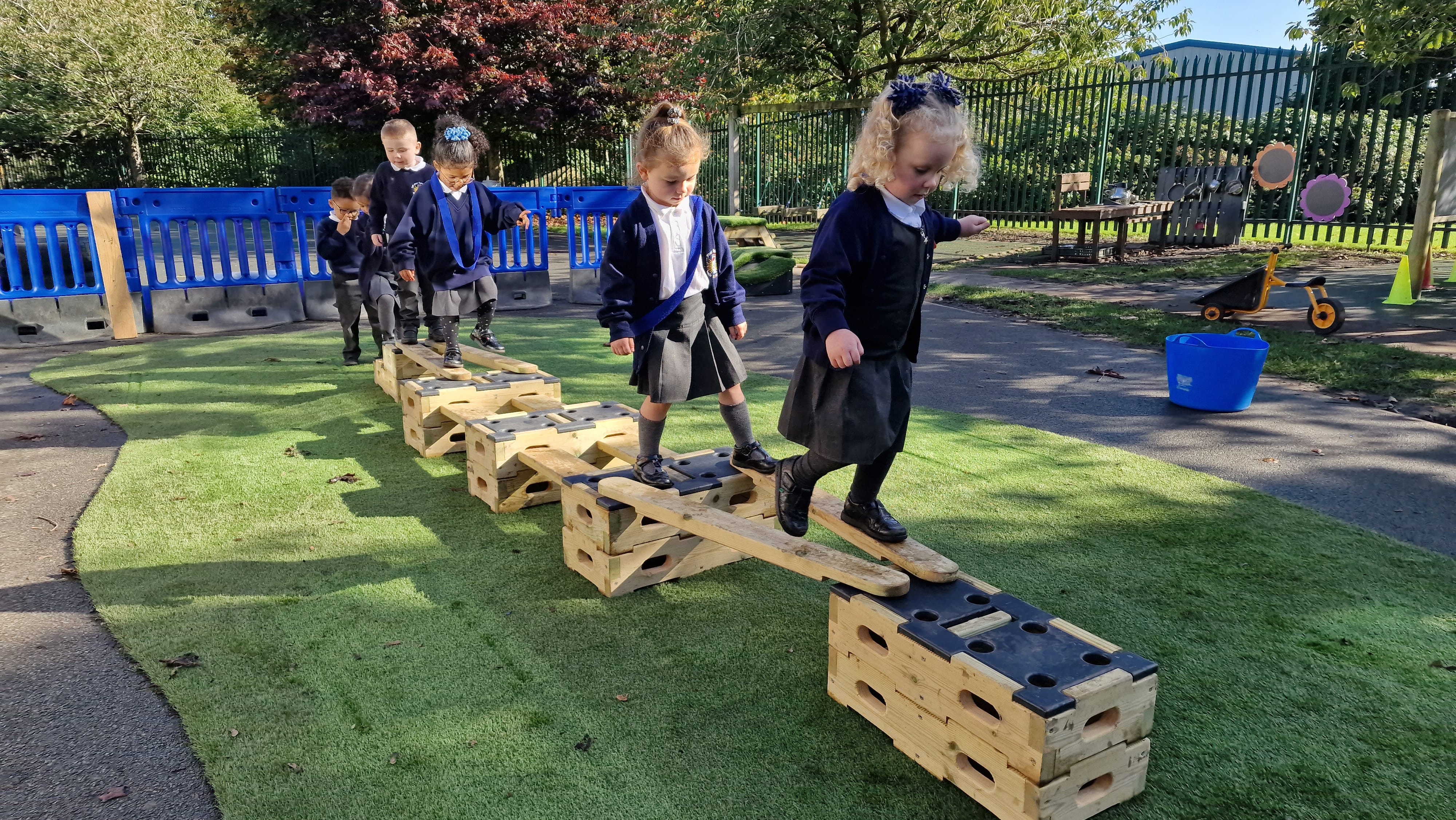 A line of school children are tackling an obstacle course that has been created from the parts of a Play Builder.