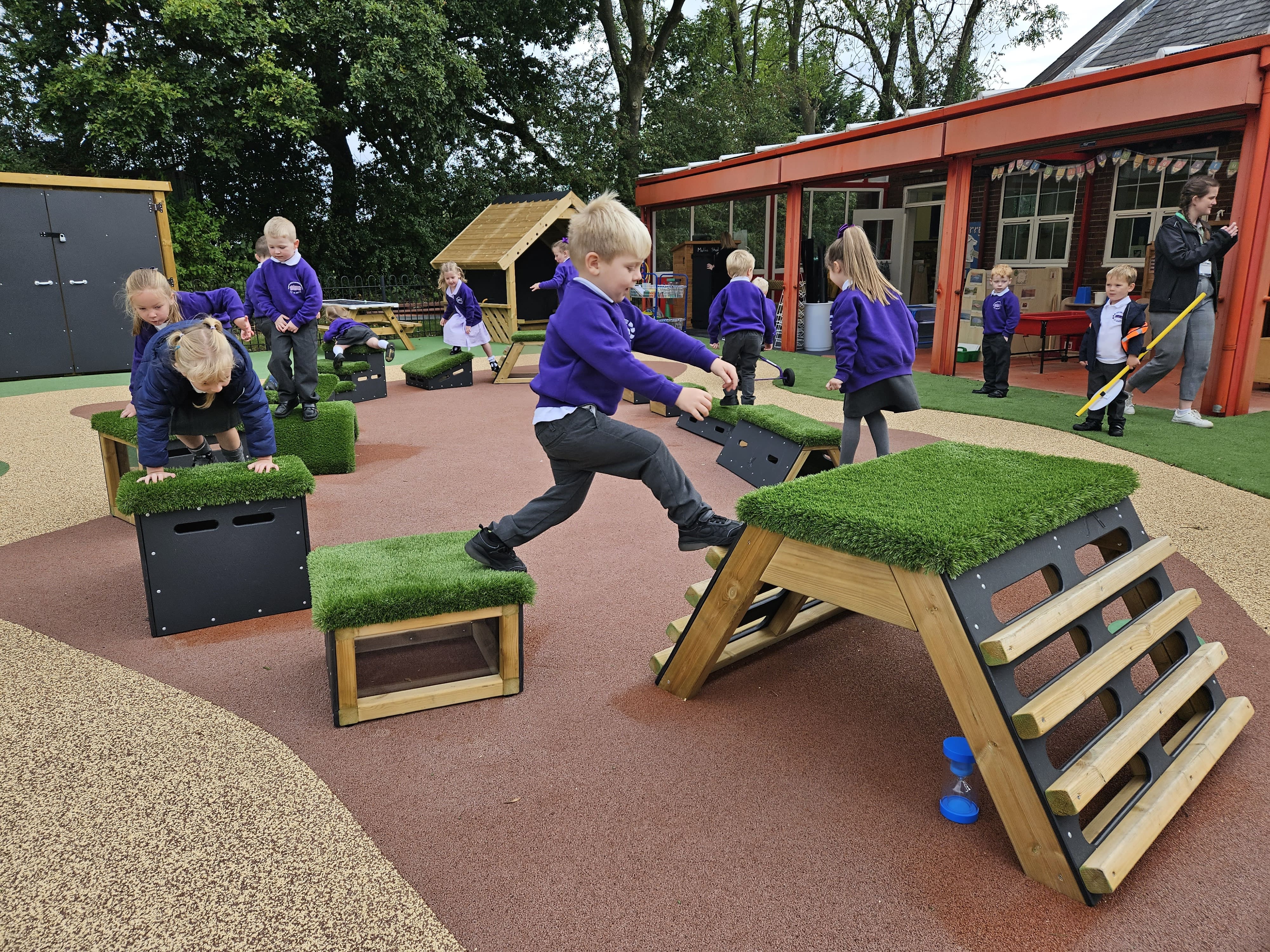 A group of children are making their way through an obstacle course that has been created from the blocks included in a Get Set, Go! Blocks Set.