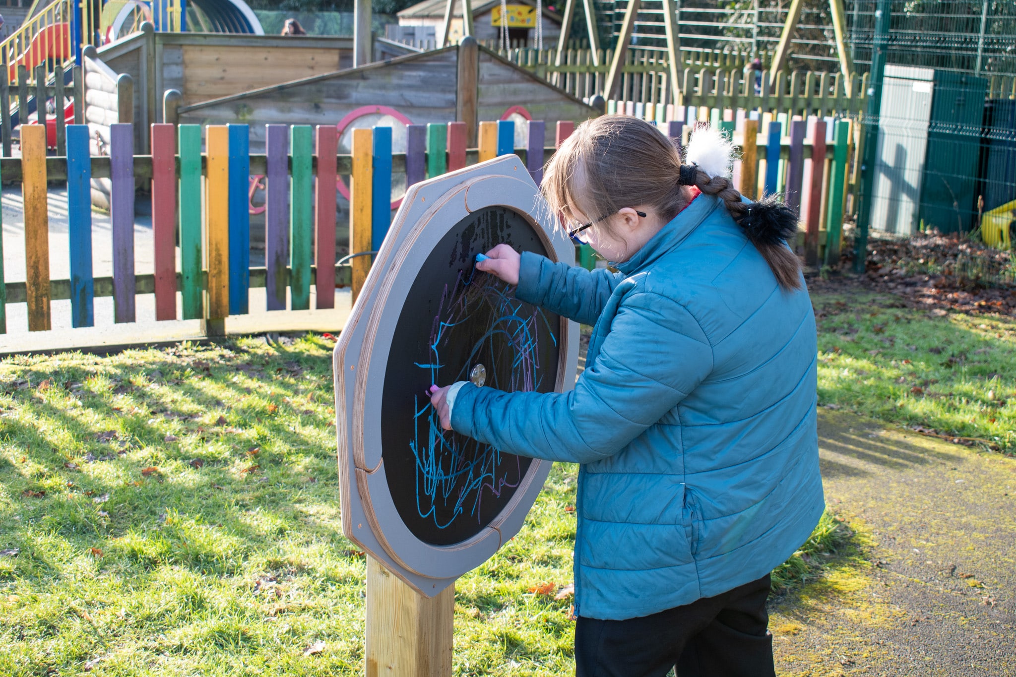 A girl with SEN is using chalk on the Drawing Sensory Spinner.