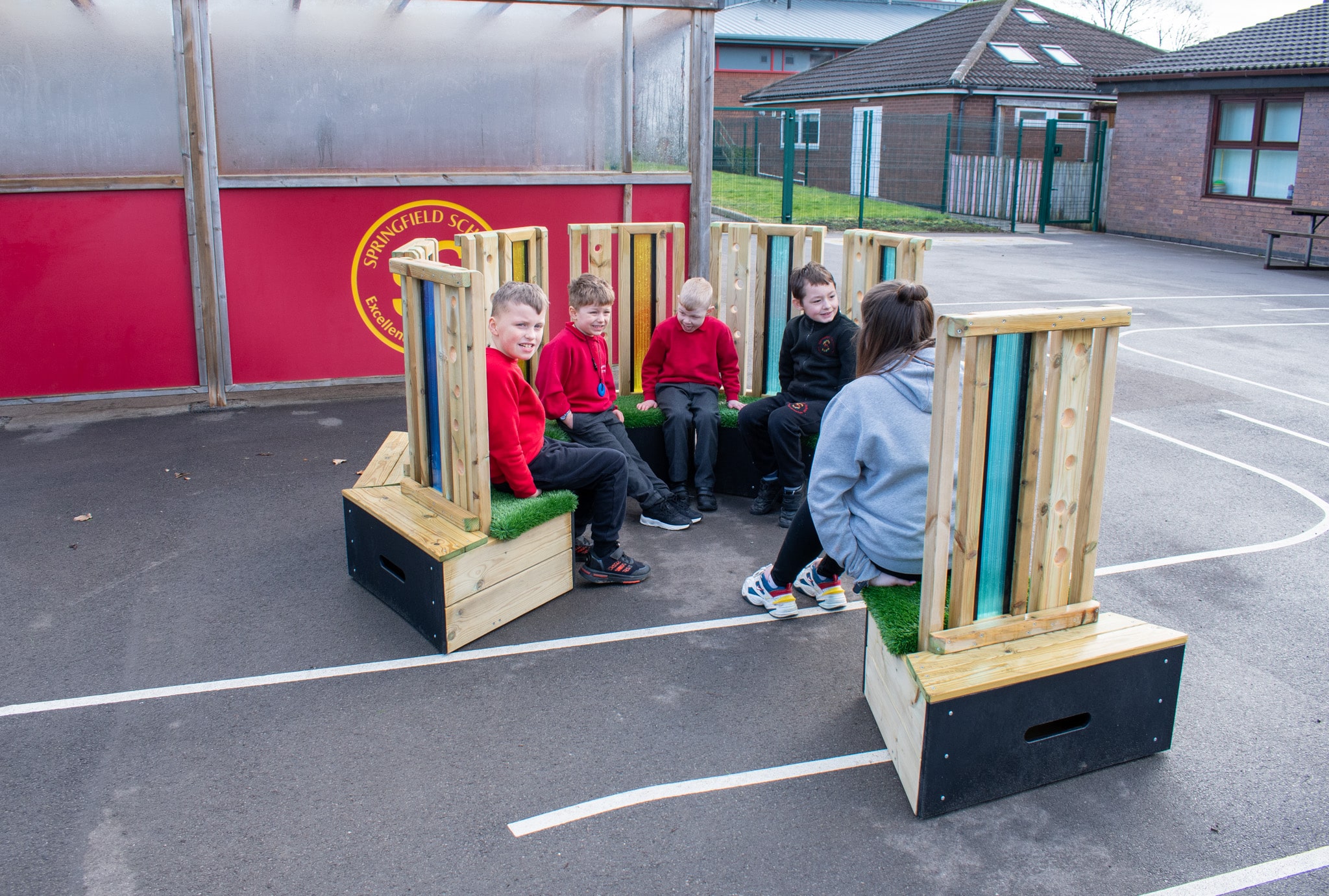 A teaching assistant is at with a group of 4 SEN children as they sit on the Sensory Seating Circle