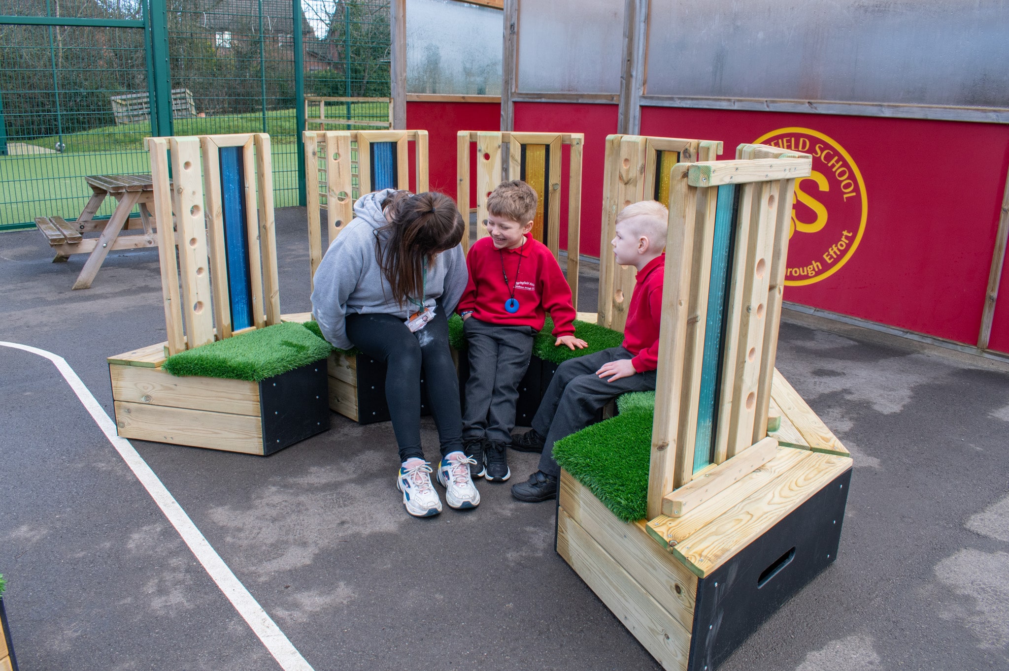 A teaching assistant is sat with two SEN boys as they all sit on the sensory seating circle.