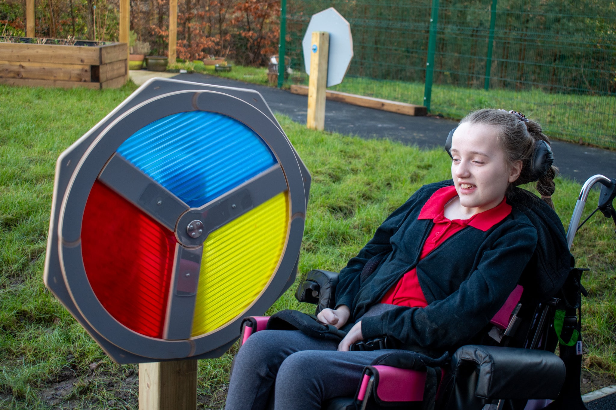 A girl with additional needs is on a wheelchair next to the Light Sensory Spinner, engaged with the visual