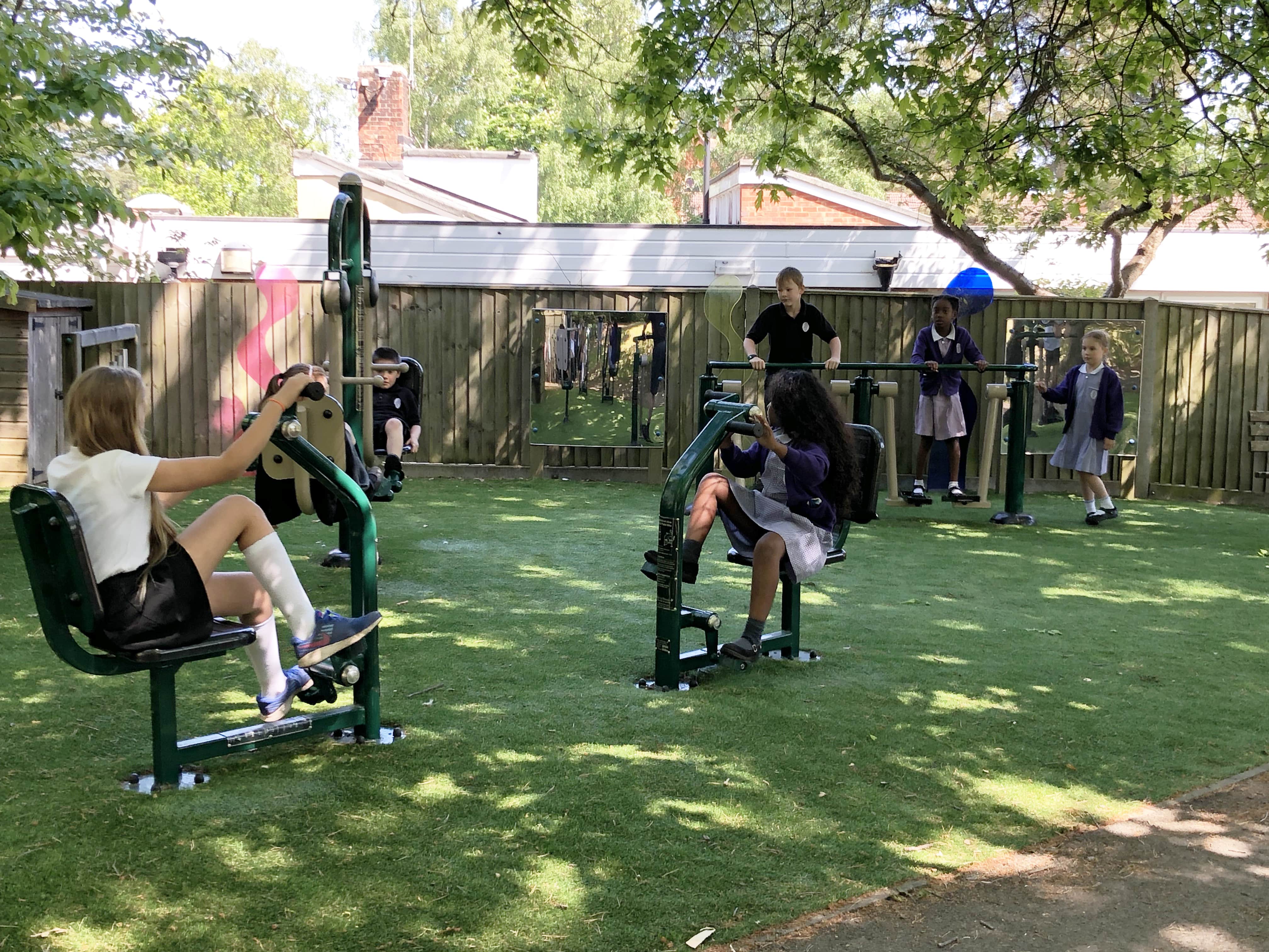 A small group of KS2 children are using school outdoor gym equipment to work out.