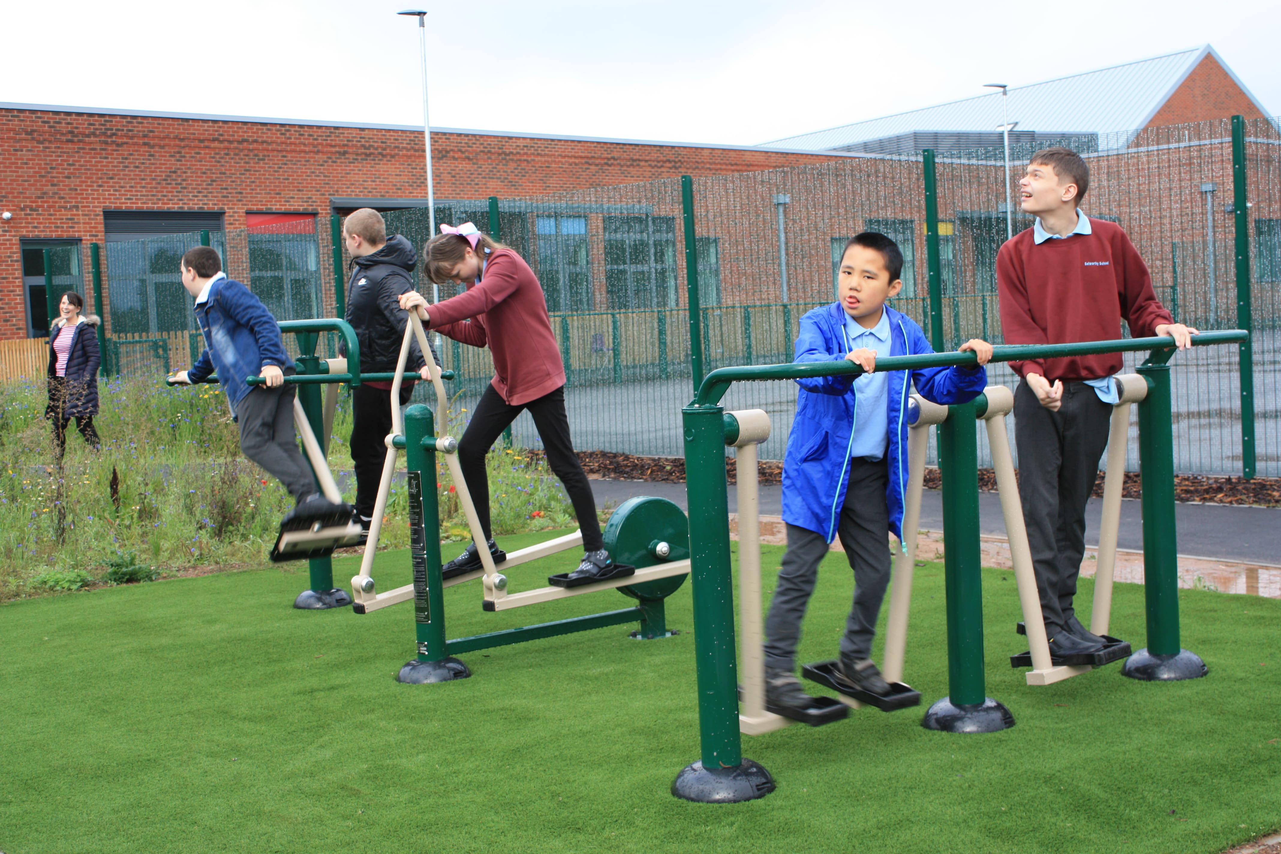 A small group of SEN children are playing on inclusive outdoor gym equipment.