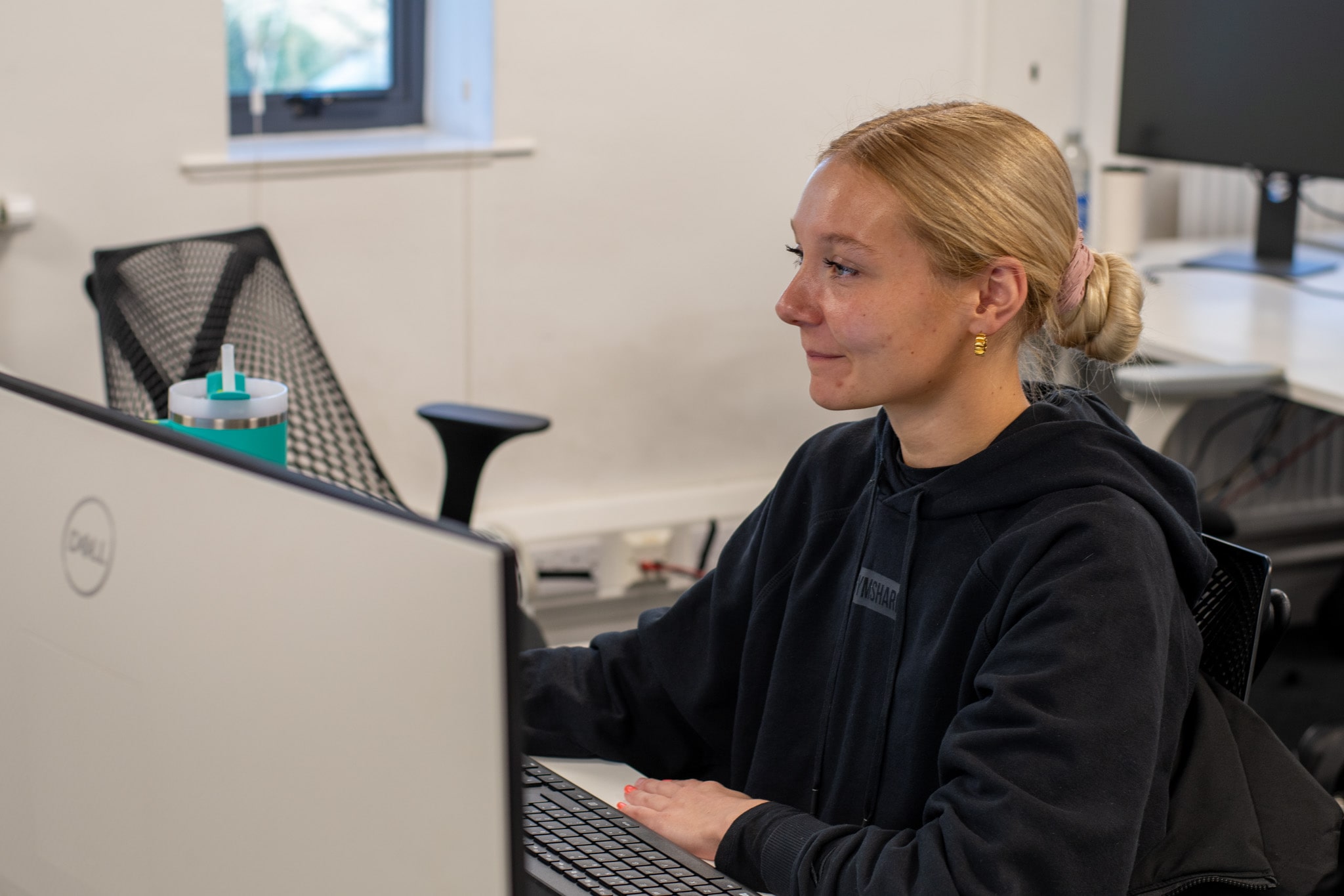 Suzie Thornley is working on her desktop as she smiles whilst looking at the screen.