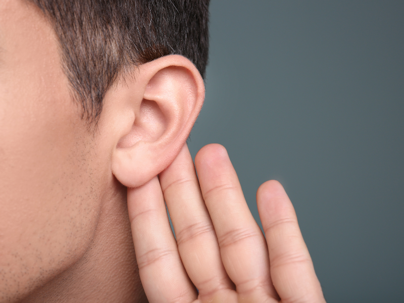 A boy is holding up his hand to his ear to signify that he can't hear.