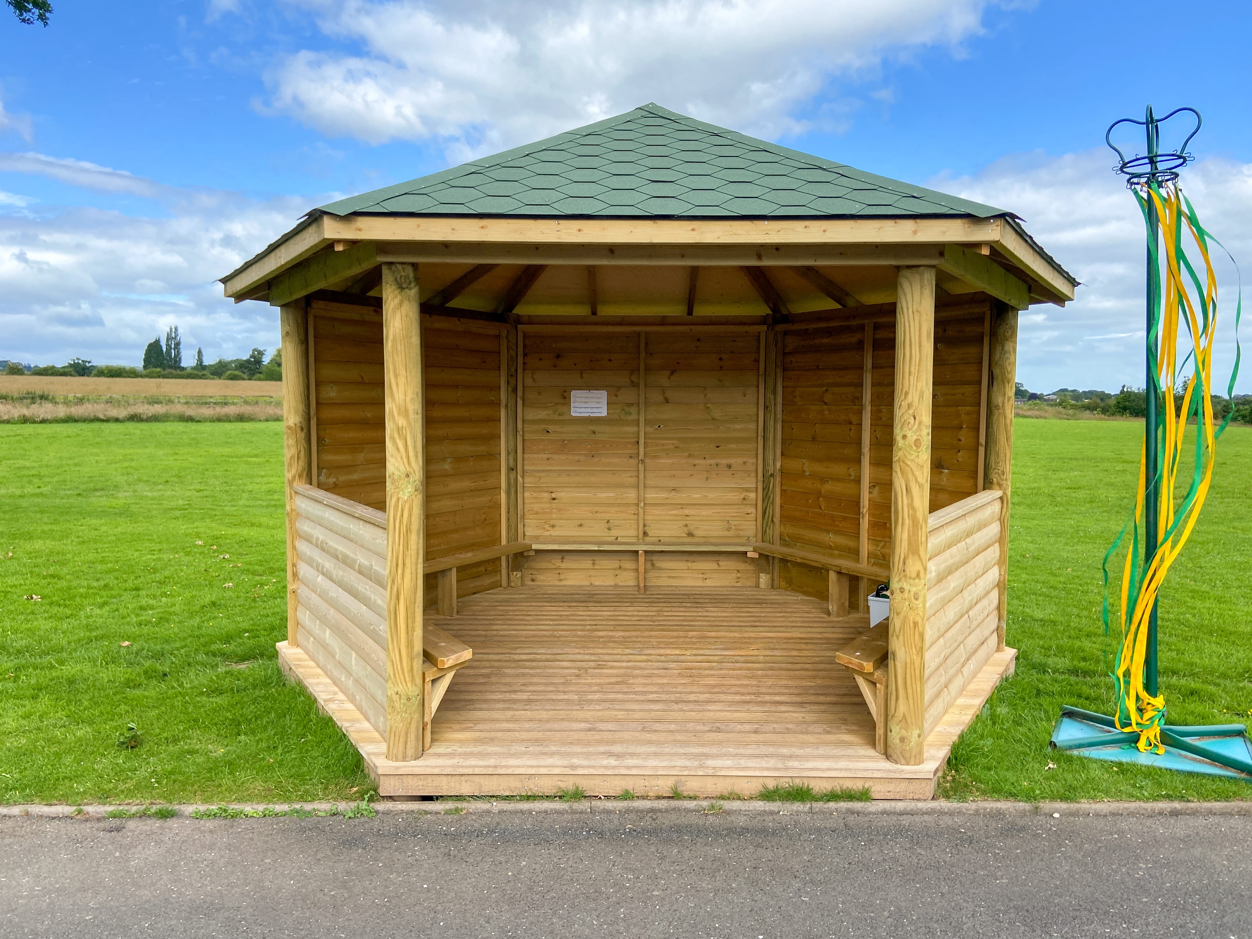 A bespoke outdoor gazebo that features installed benches and picket fencing around the structure.