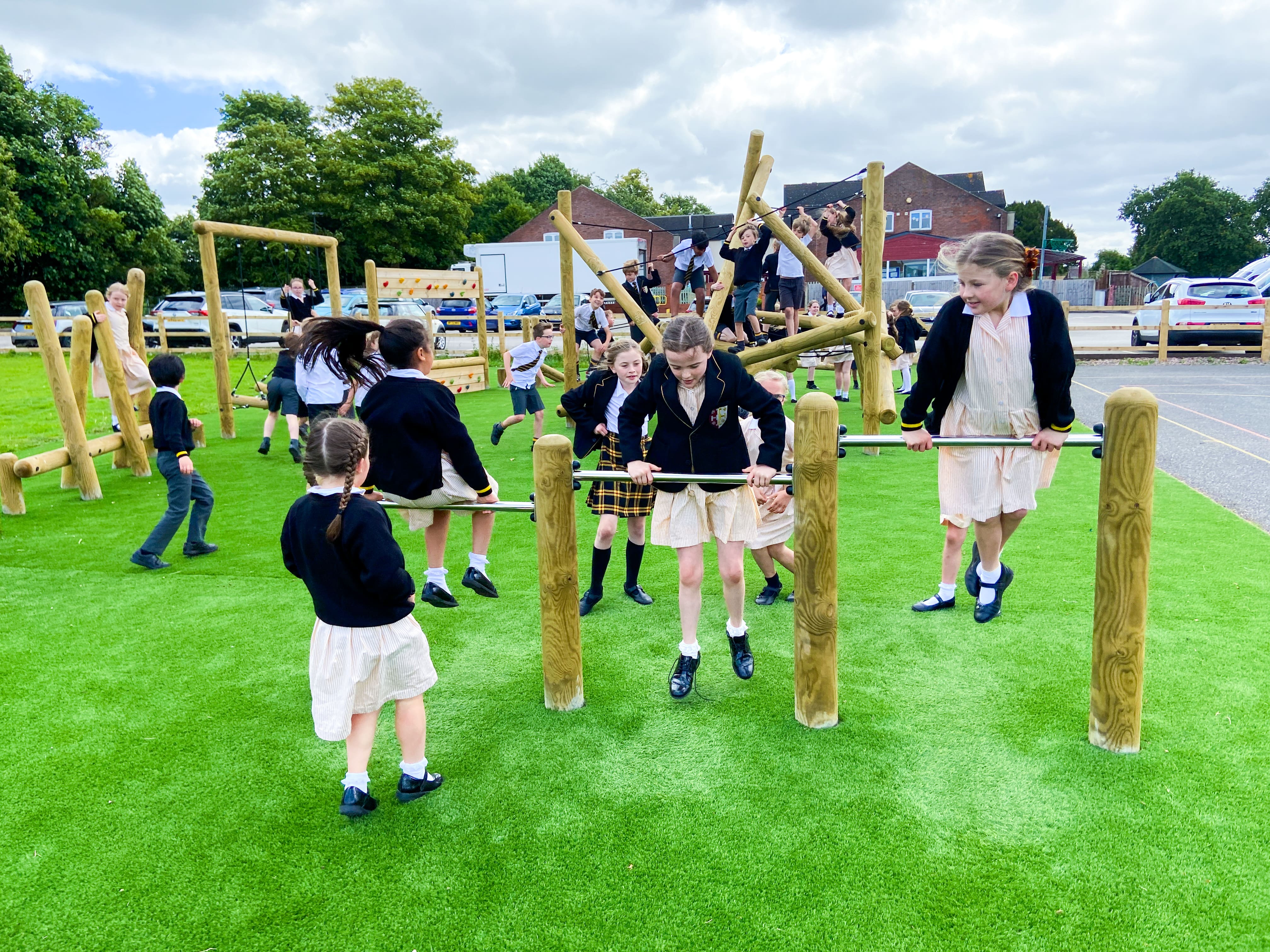 A few children are playing on the Forest Roll Over Bars that have been incorporated within the bespoke trim trail.