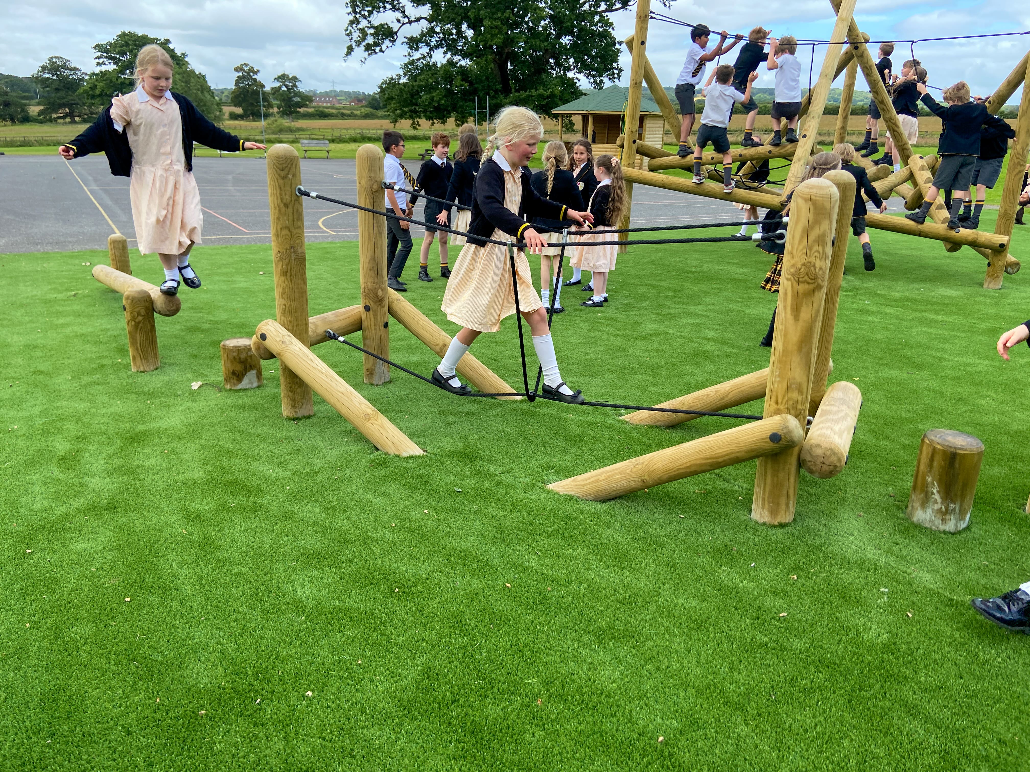 A child is crossing the rope bridge as another child is waiting for their turn.