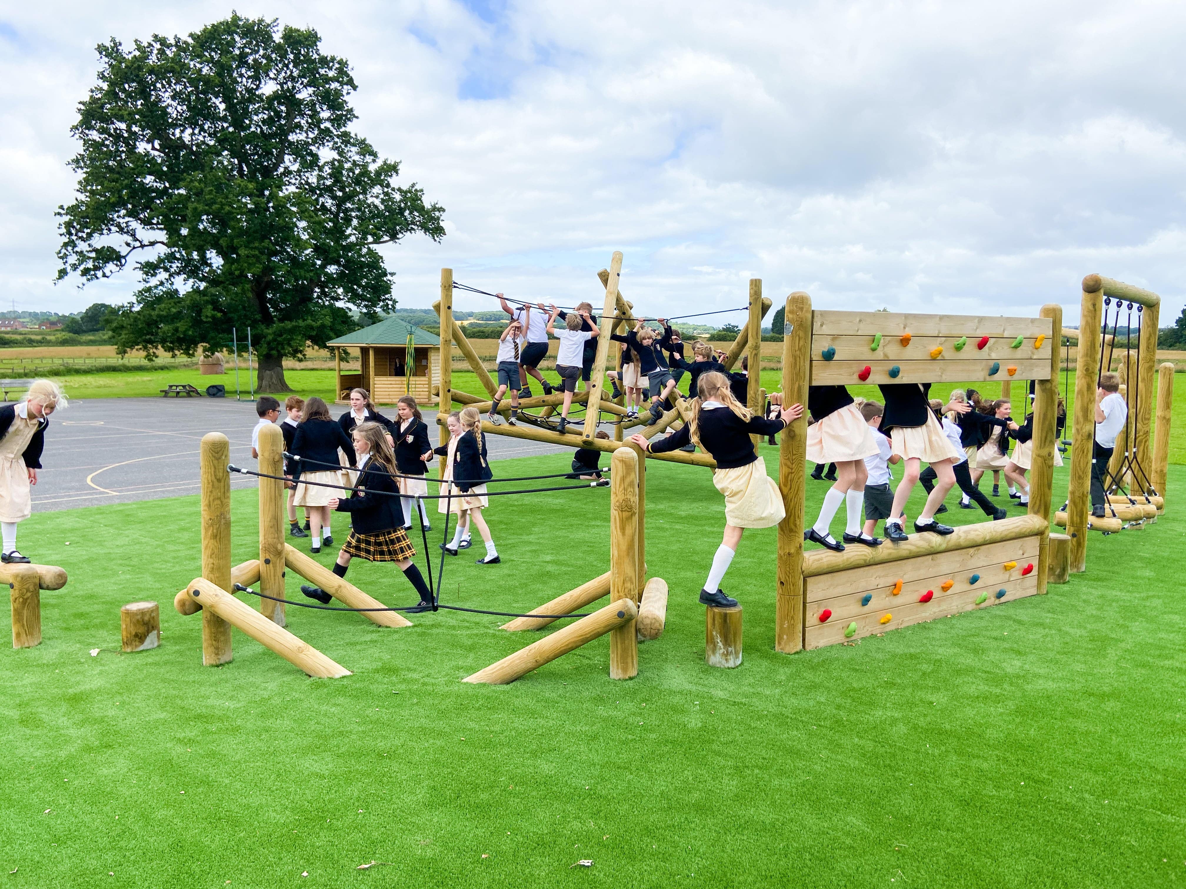 A group of children are navigating their way through the bespoke trim trail, featuring a variety of active play equipment.