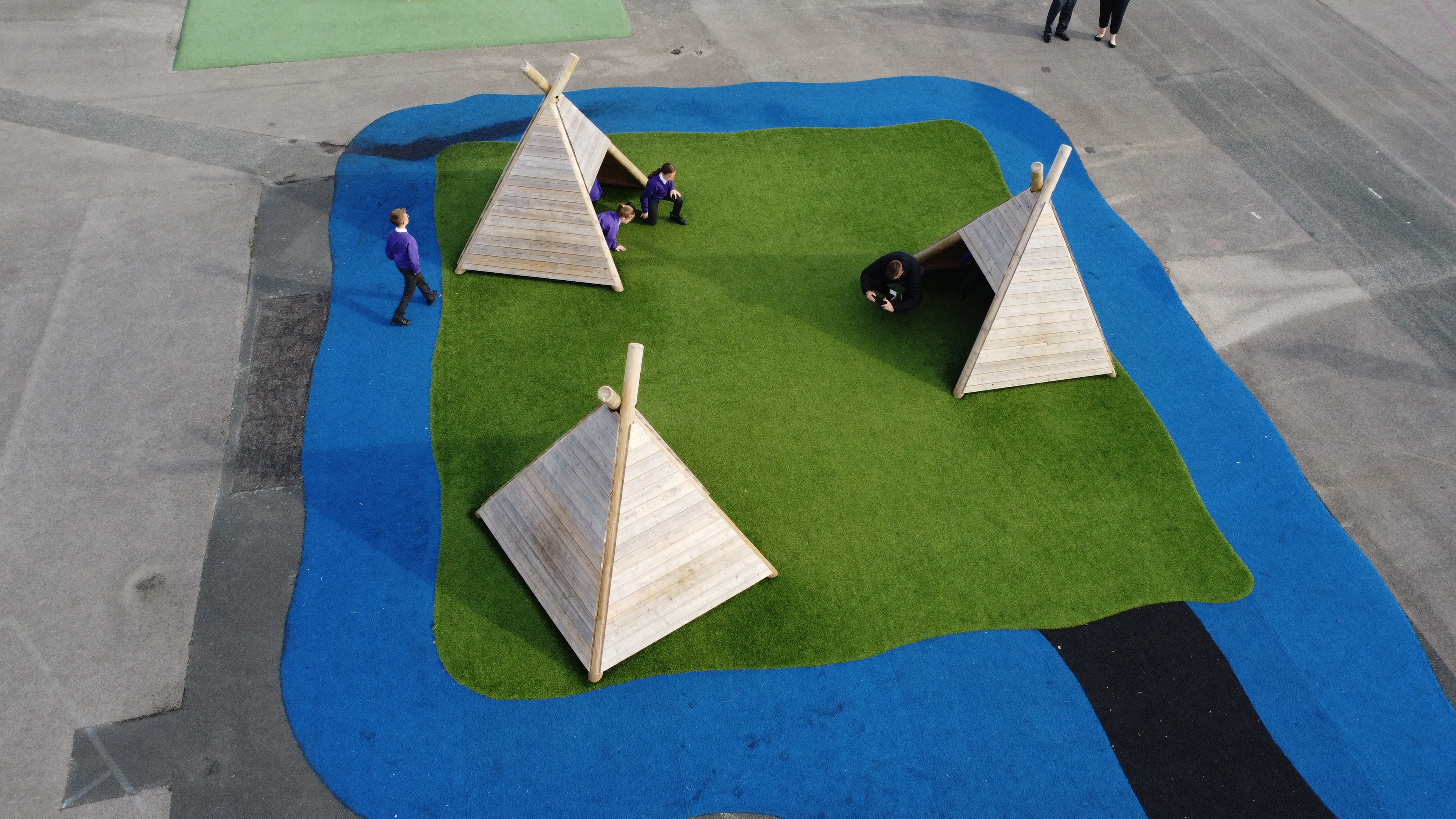 A safeturf surface with Wigwams on top of it. The Saferturf has been laid in the design of an island surrounded by water.