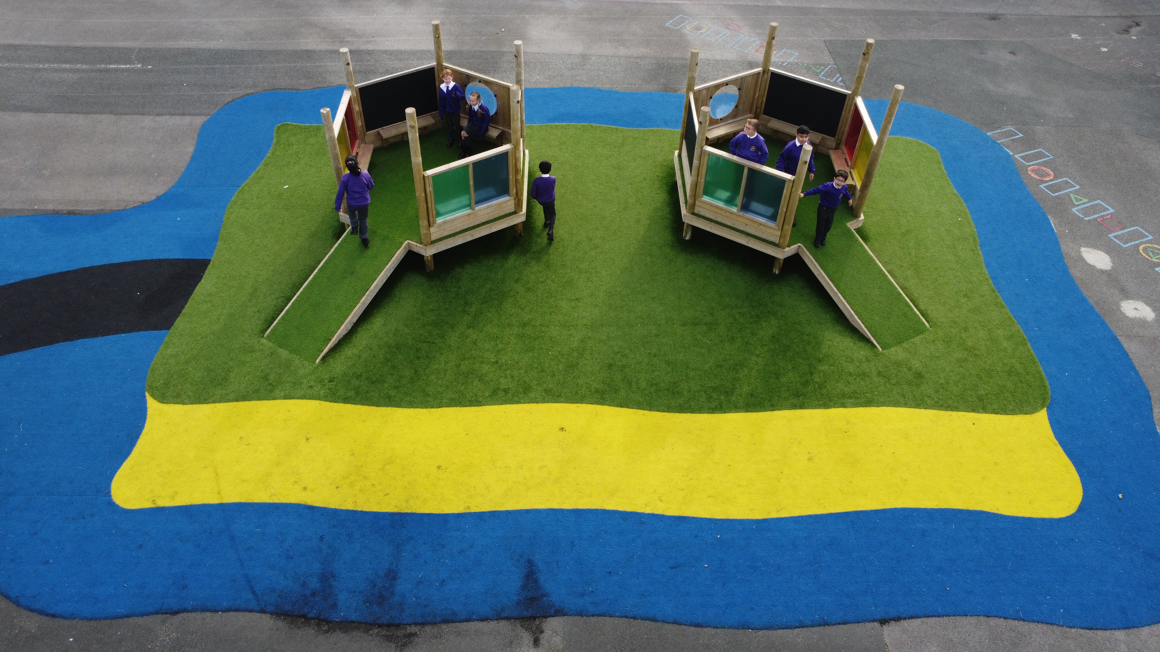 A saferturf surface that has been designed to look like an island with a beach. Two Imagination Stations have been placed on top.