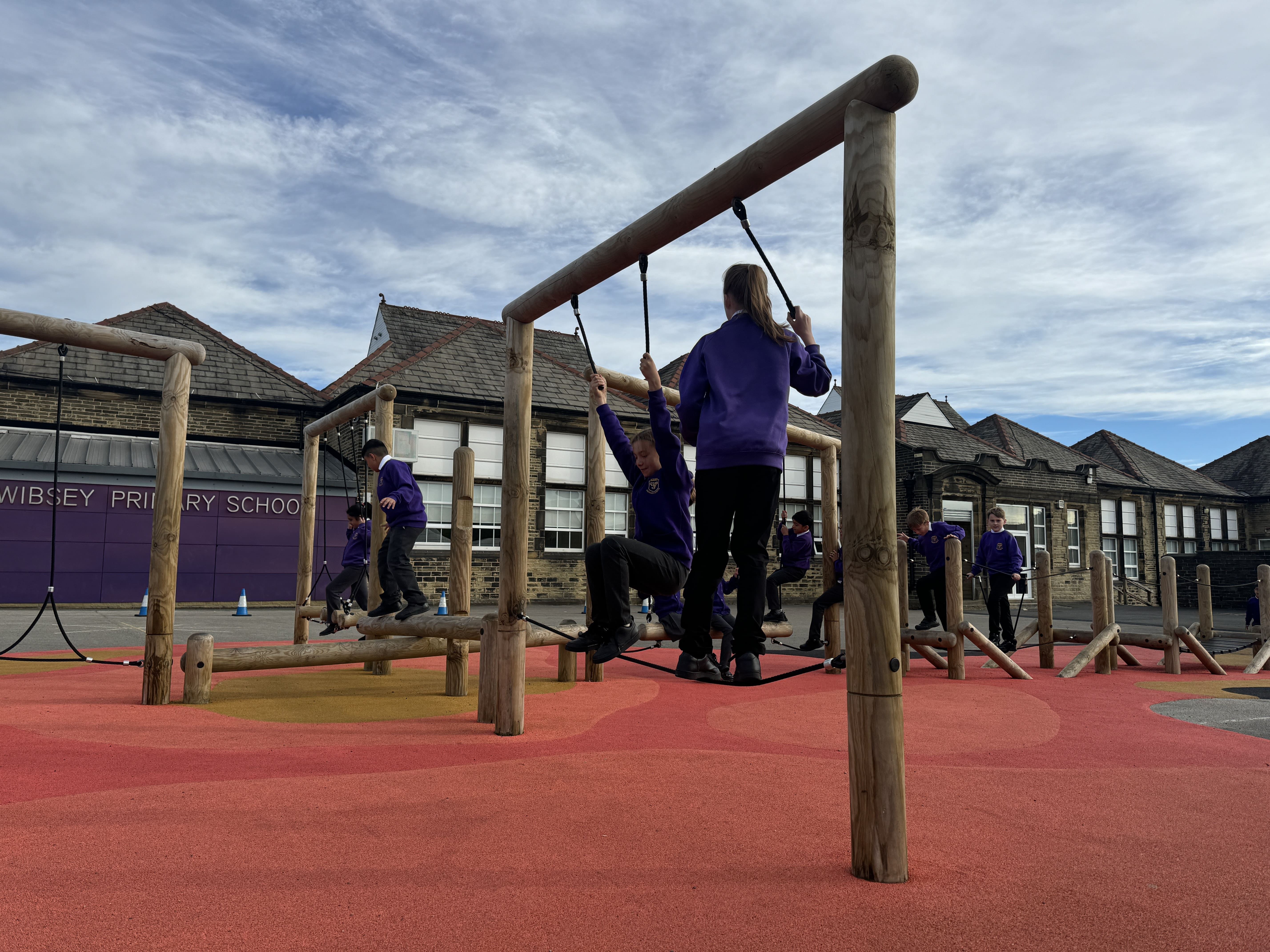 Children are climbing along the trim trail that has been installed on a wetpour surface.