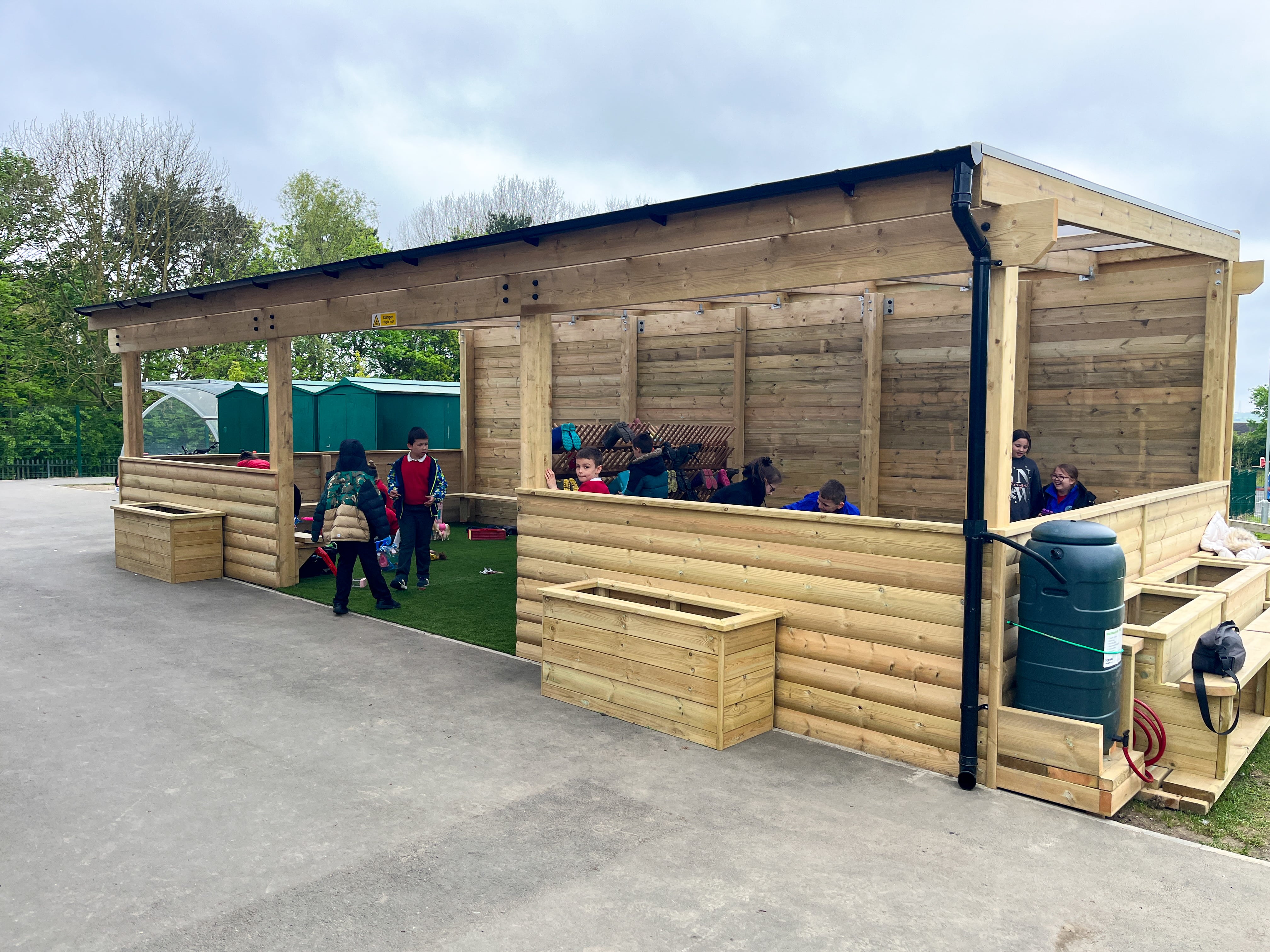 A freestanding timber canopy that has a water draining system, that connects to a storage container with a hose pipe connected to it.