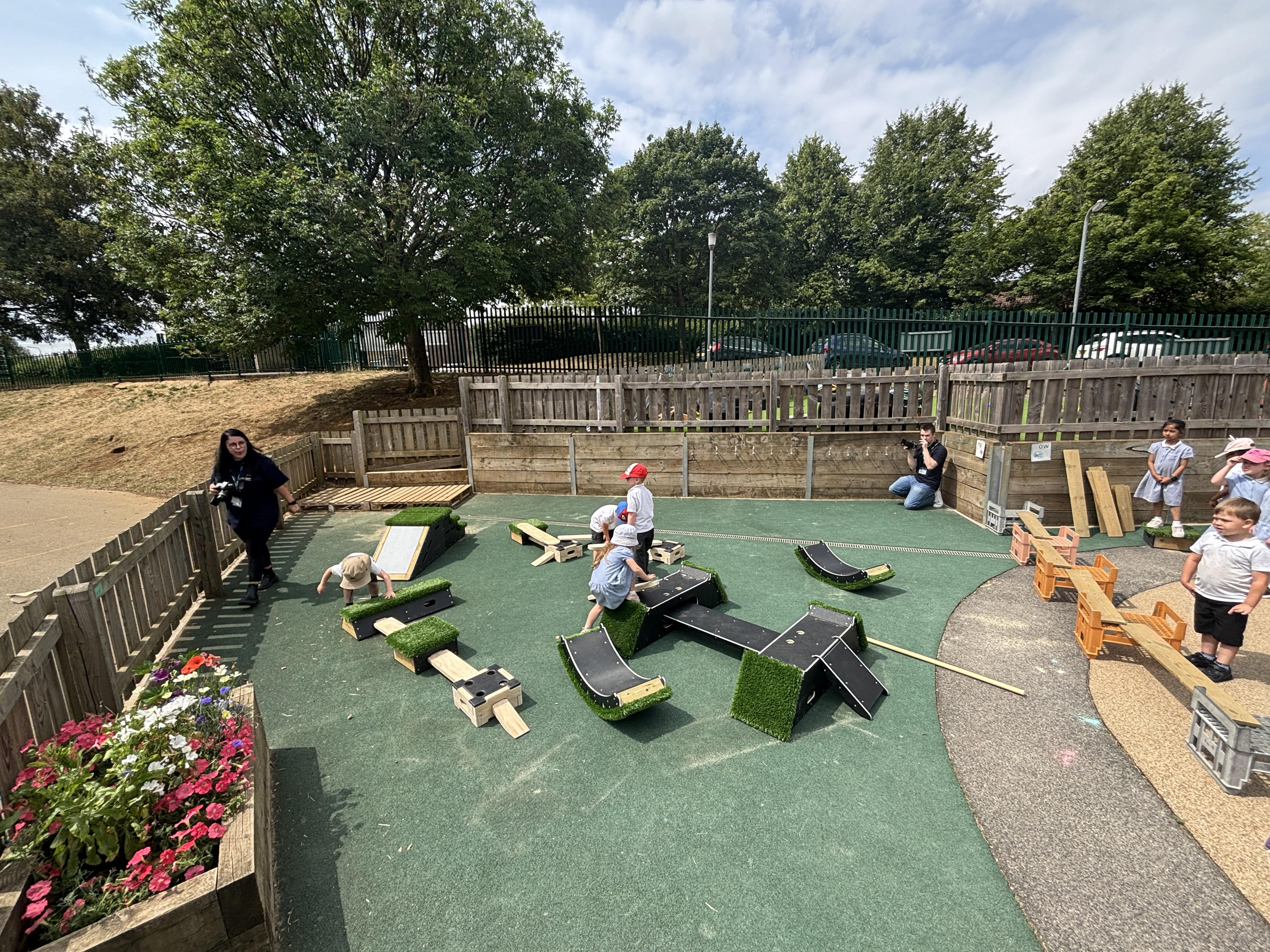The play equipment is all set up on an EYFS playground with Pentagon Play staff walking around and taking pictures.