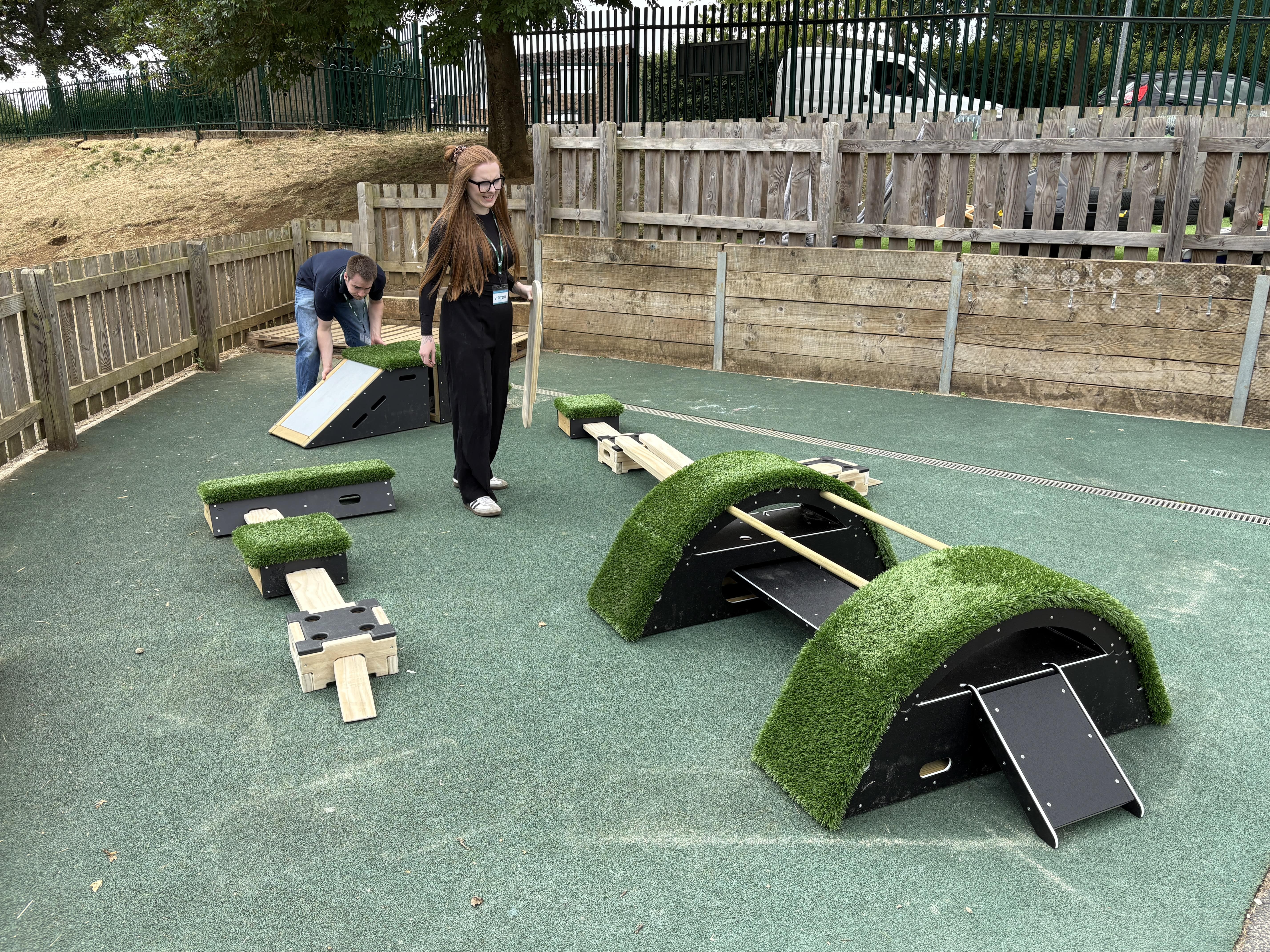 Maddy McGuire and a member of the marketing team, are setting up the play equipment on the playground.