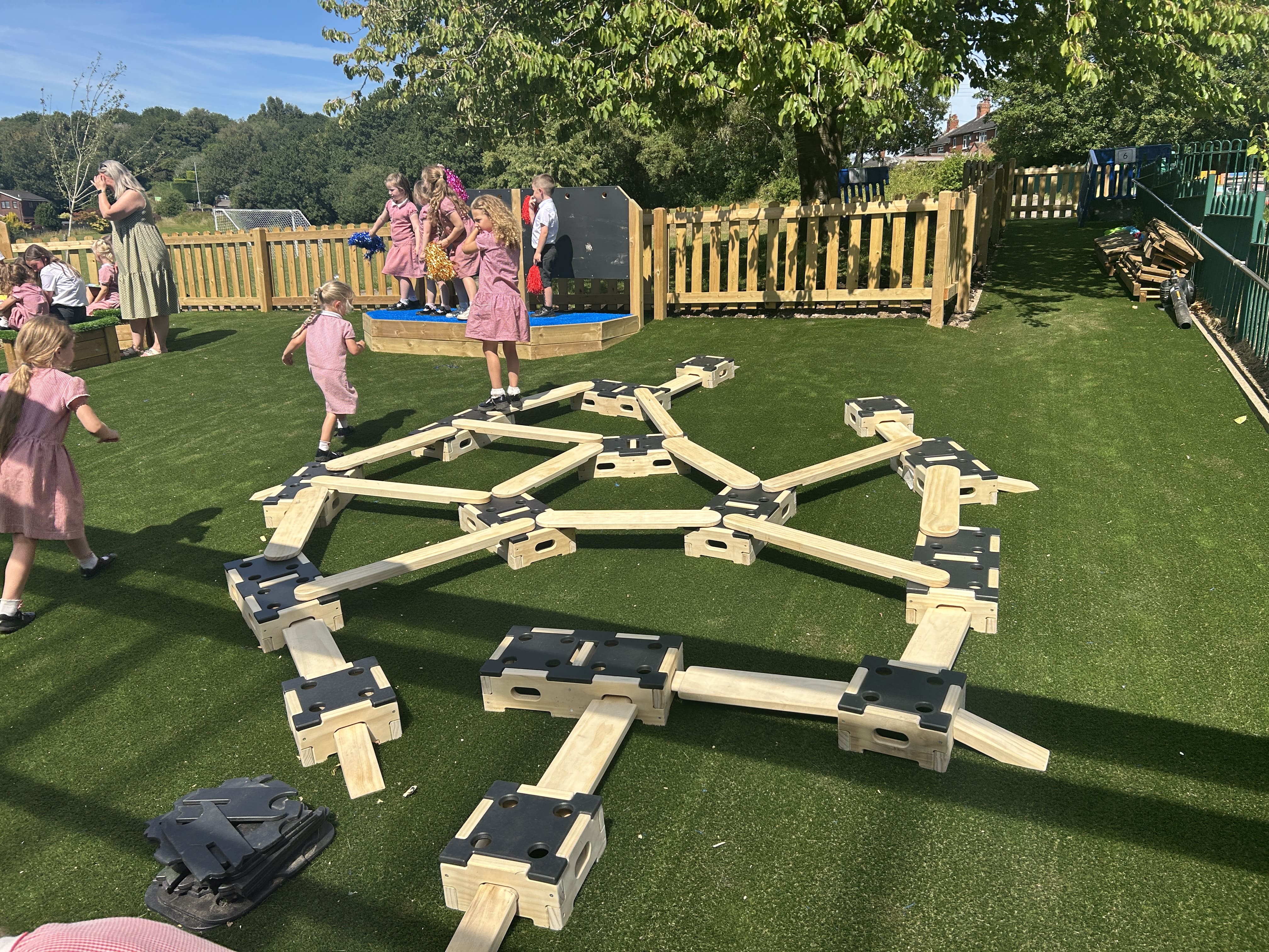 A group of EYFS children are playing with the Play Builder set, as another group is performing on the Performance Stage.