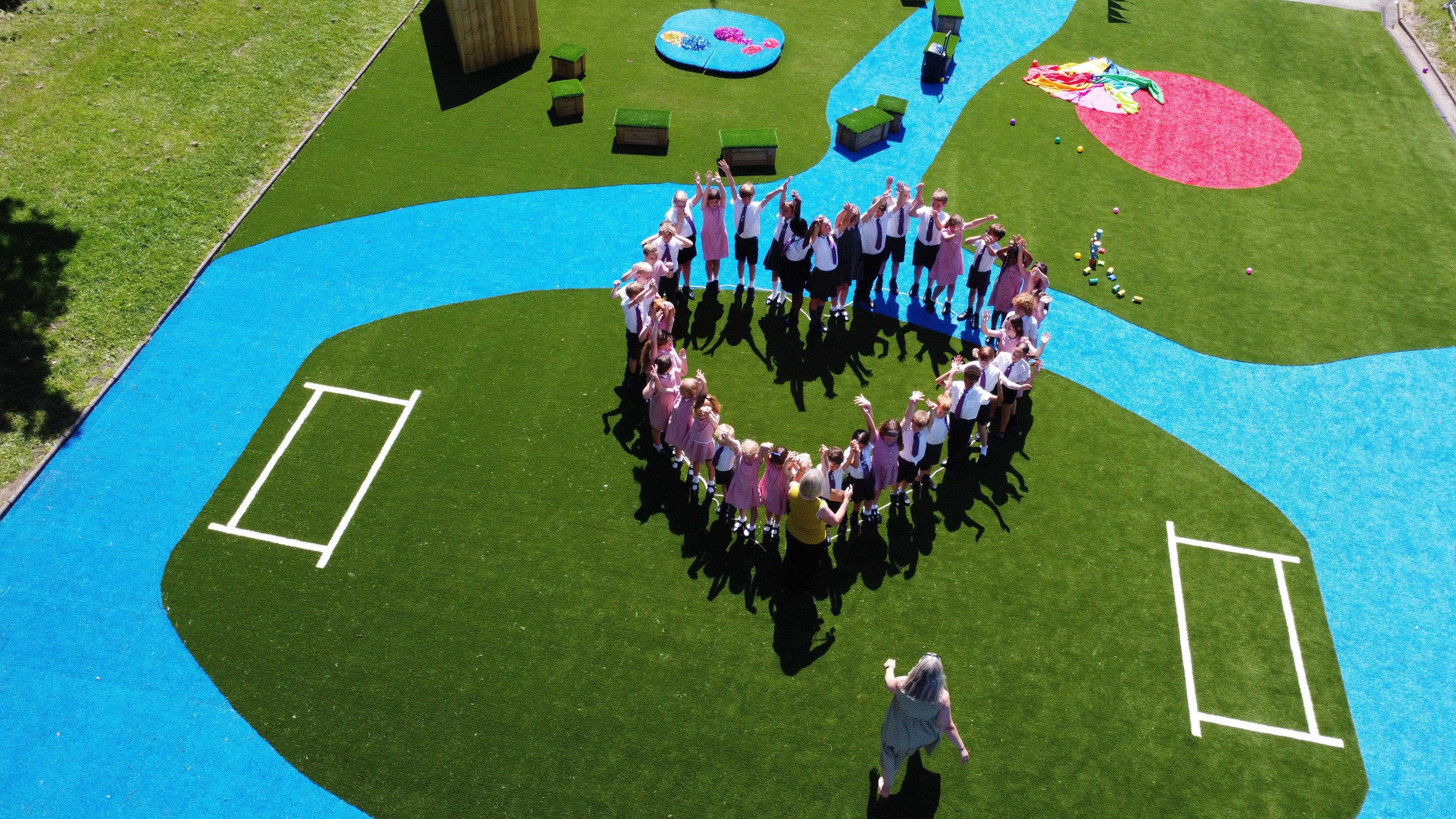 All the children are stood on the new playground in the shape of a heart.