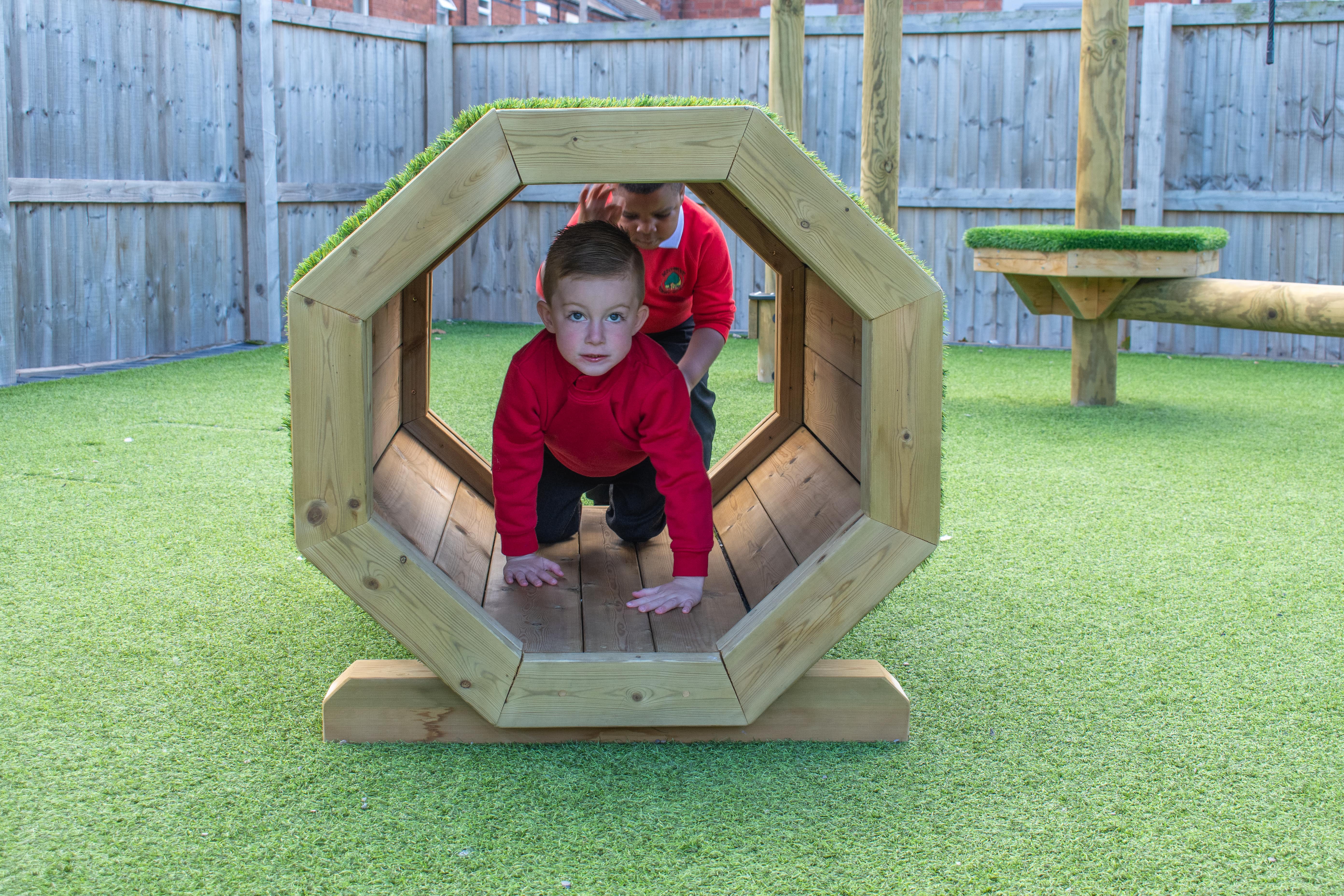 Two little boys are crawling through the Millhouse Octagonal Tunnel outside.