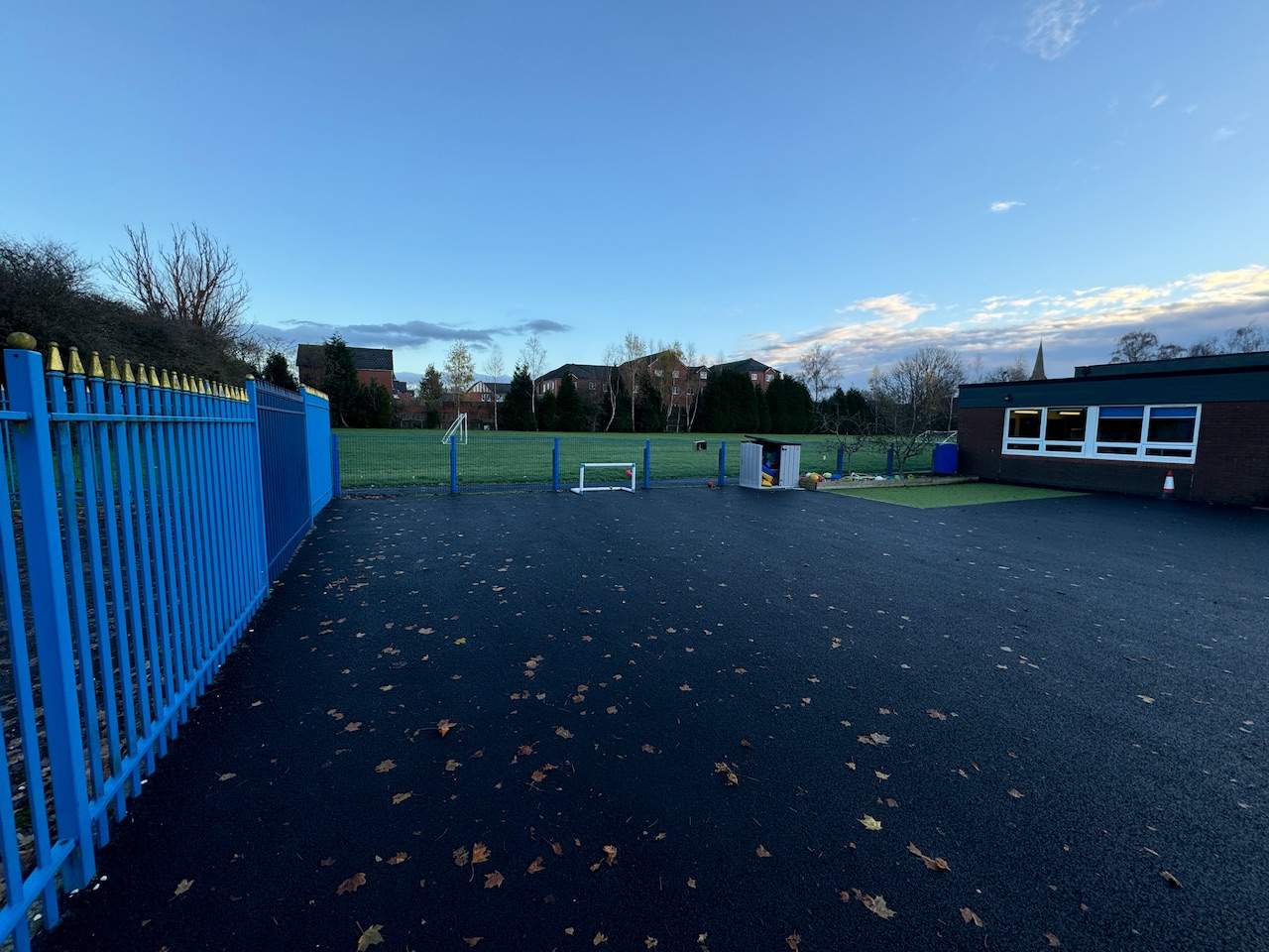 An empty and old playground at St Peter's Primary, with blue fencing all around it.